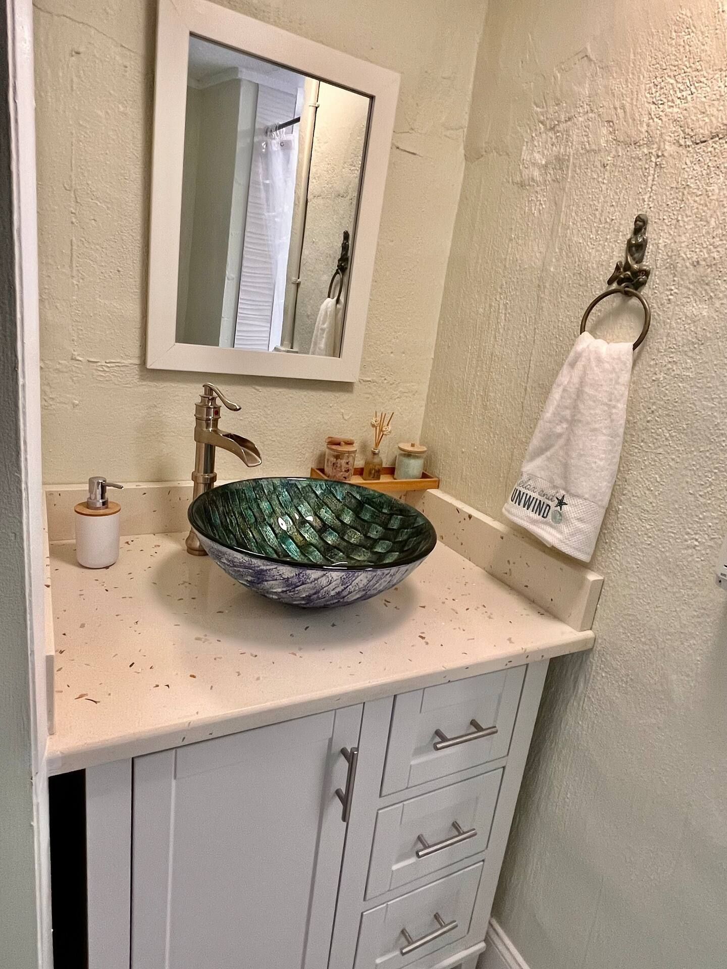 A bathroom with a sink , mirror and towel rack.