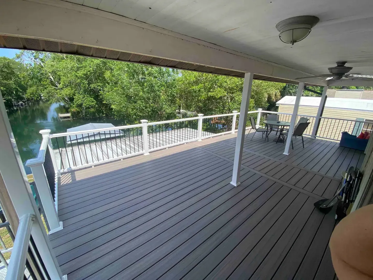 A large deck with a ceiling fan and a view of a lake.