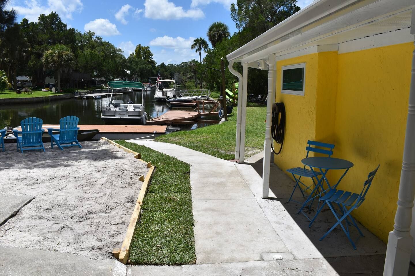 A yellow building with blue chairs and a table in front of it
