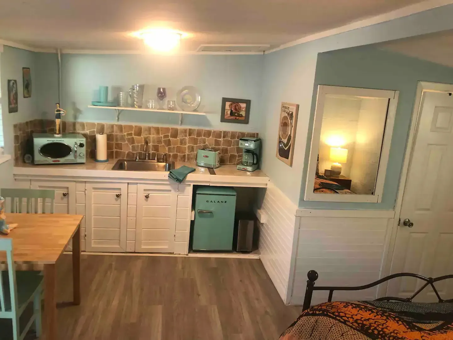 A kitchen with a sink , refrigerator , microwave , table and chairs.