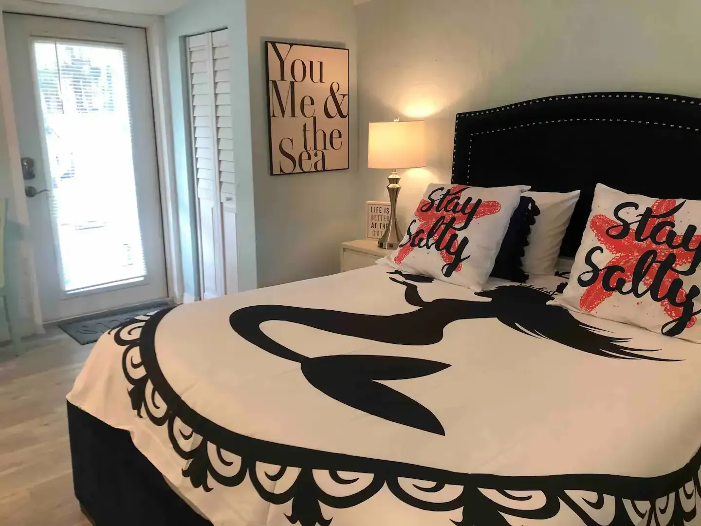 A bedroom with a bed , pillows and a sign that says `` stay salty ''.