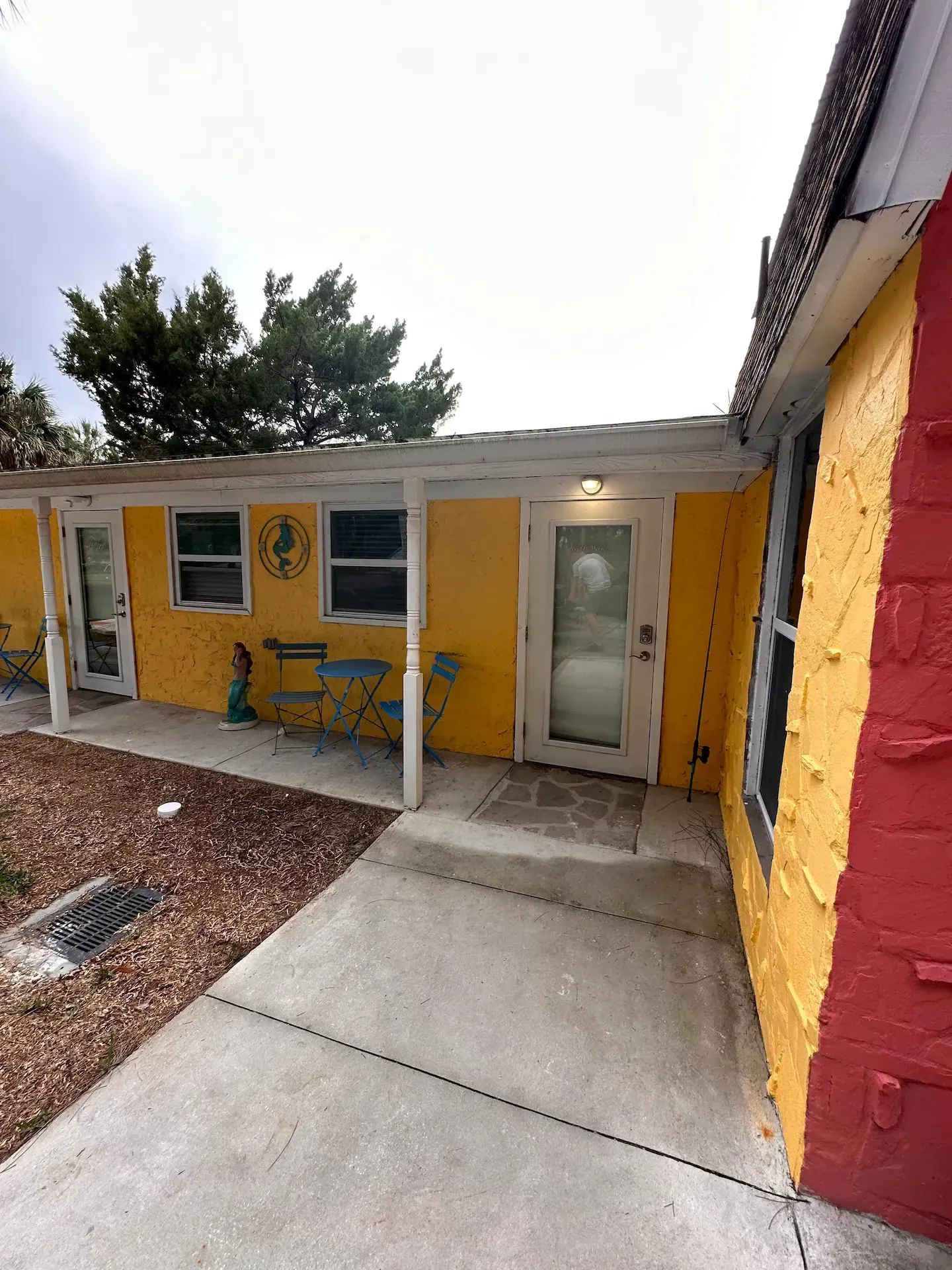 A yellow house with a red door and a covered porch.