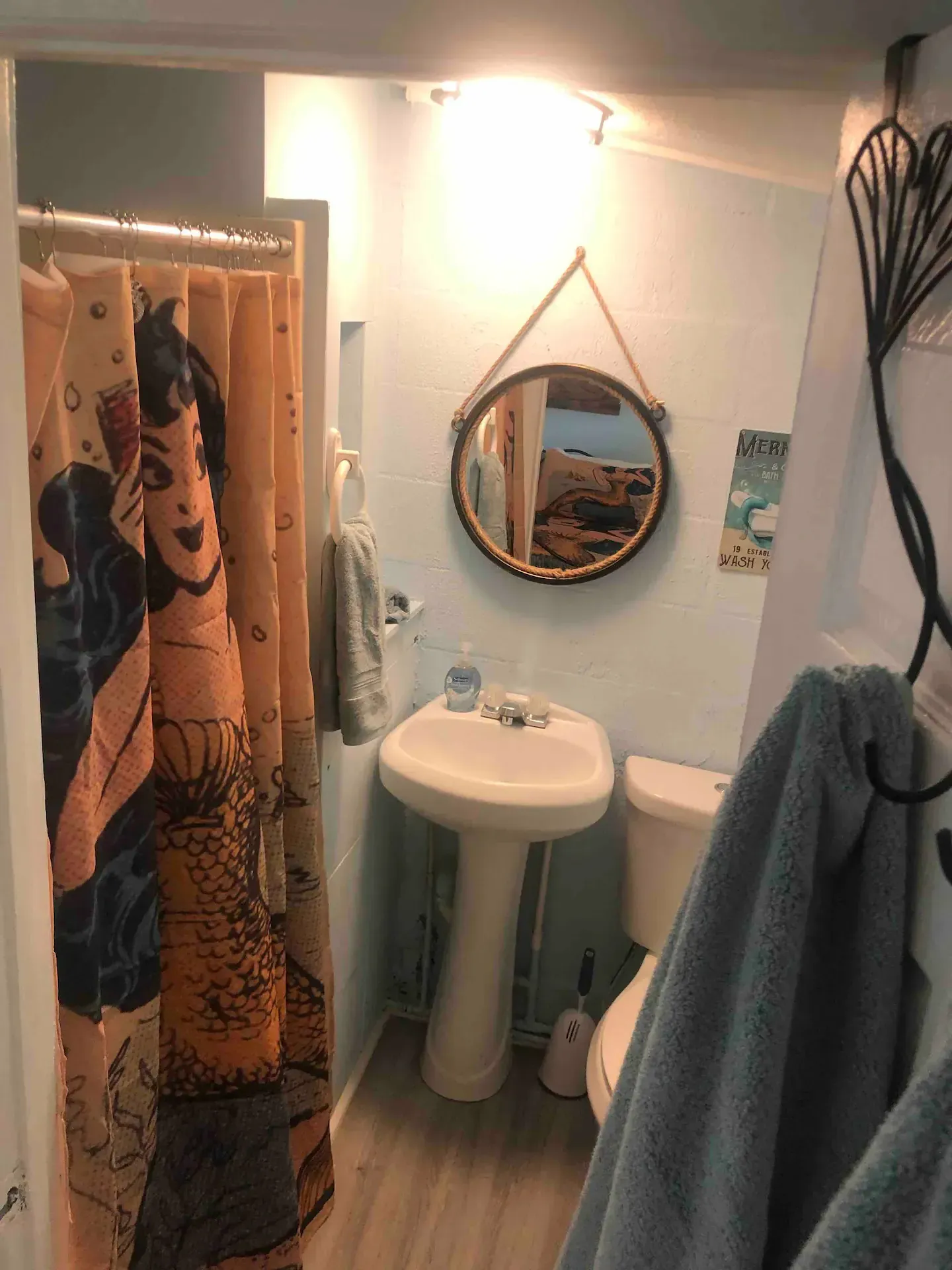 A bathroom with a sink , toilet , shower curtain and mirror.