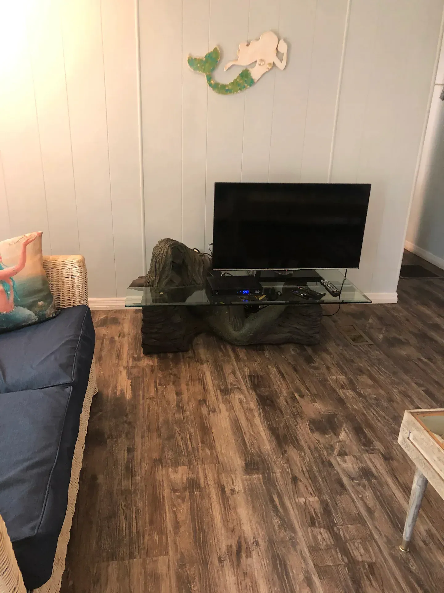A living room with a couch and a flat screen tv on a glass table.