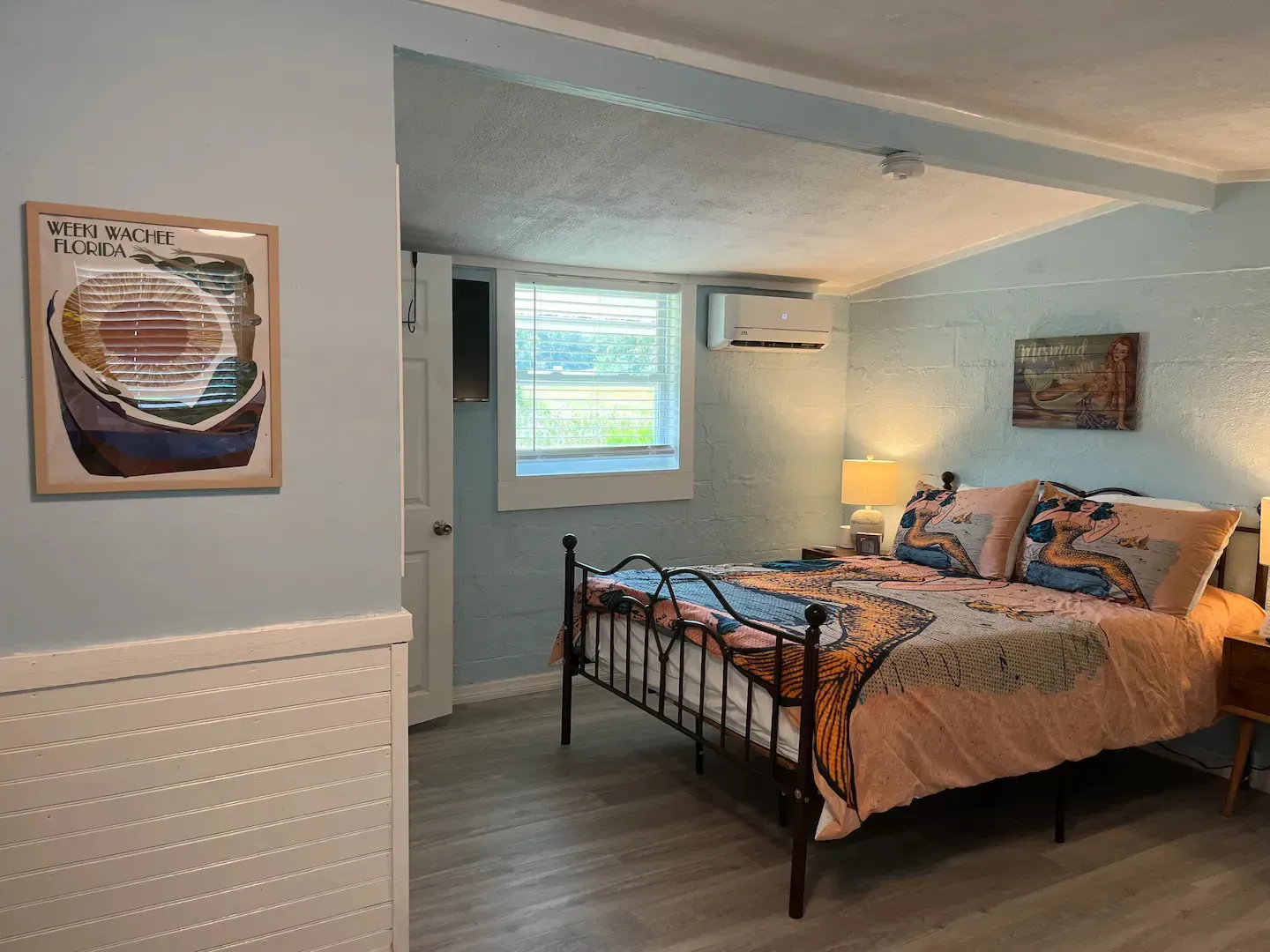 A bedroom with a large bed and a picture on the wall.