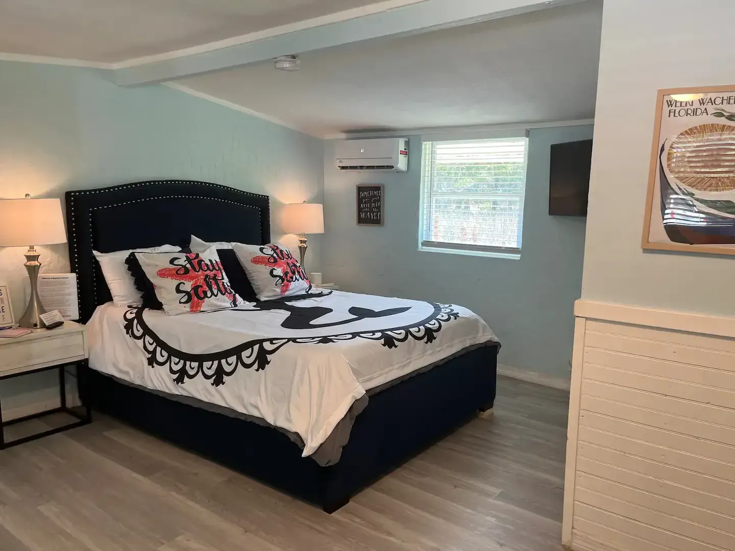 A bedroom with a bed , nightstand , dresser and window.