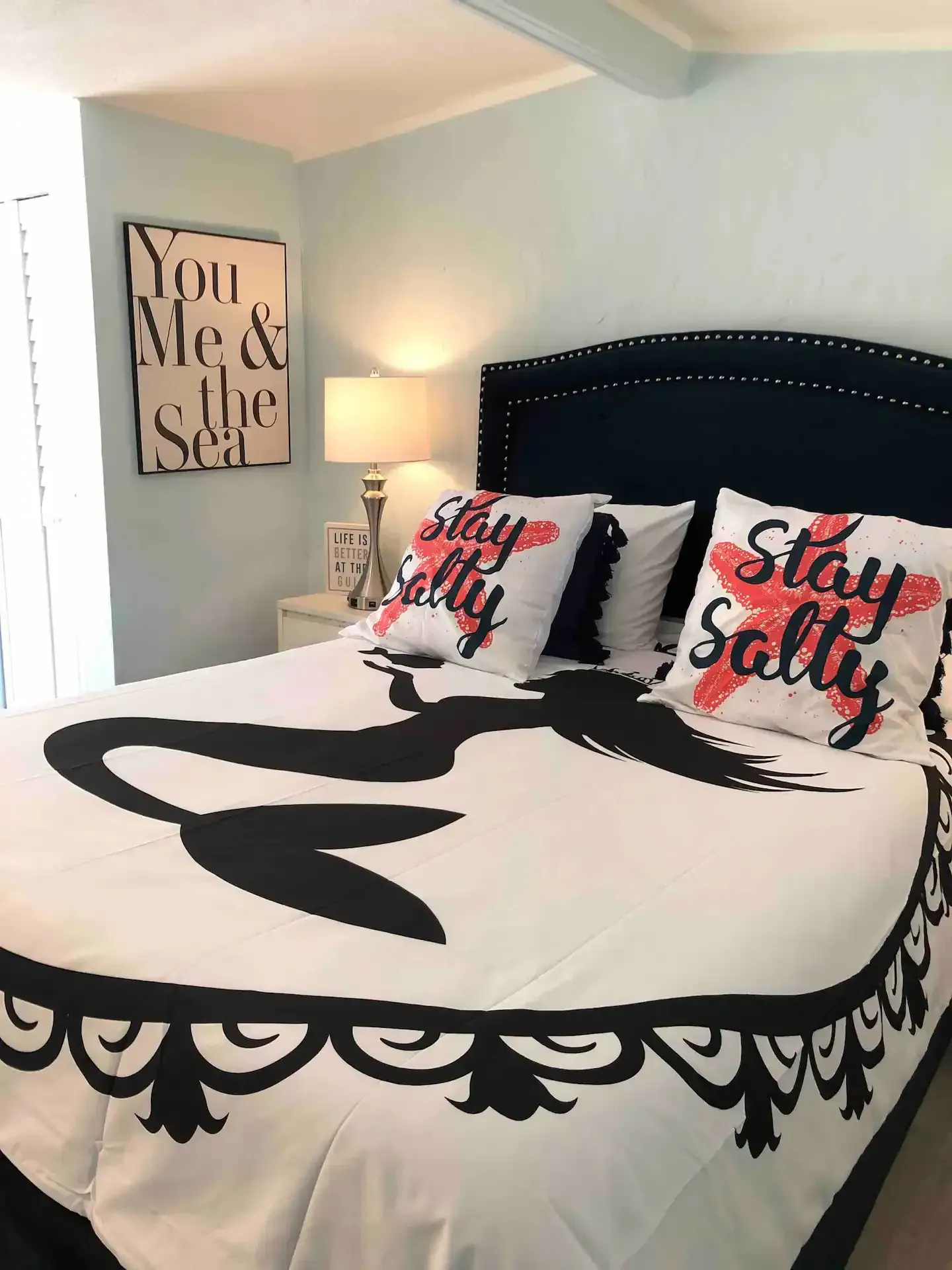 A bed with a mermaid comforter and pillows in a bedroom.