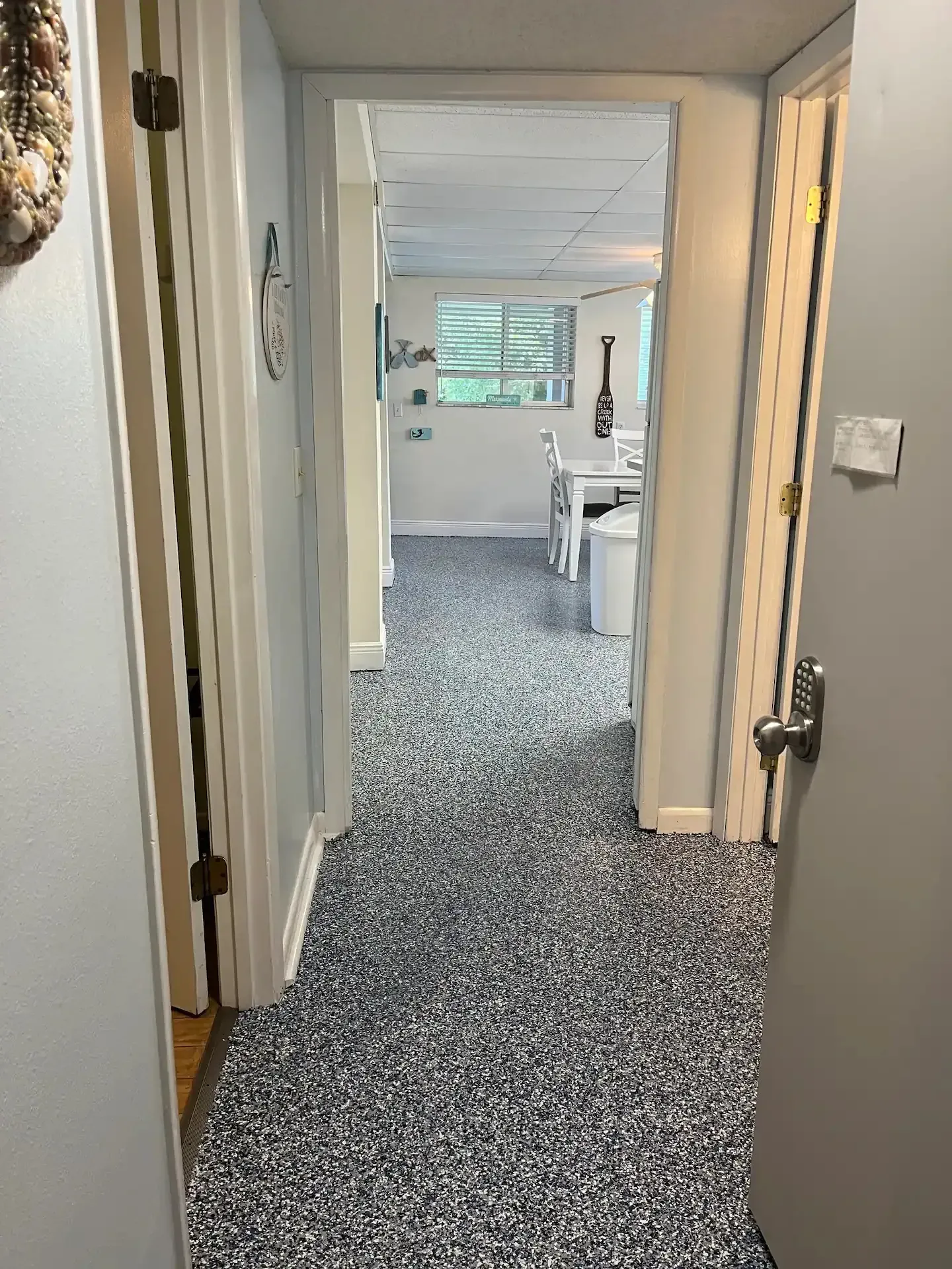 A hallway with a carpeted floor and a door leading to a room.