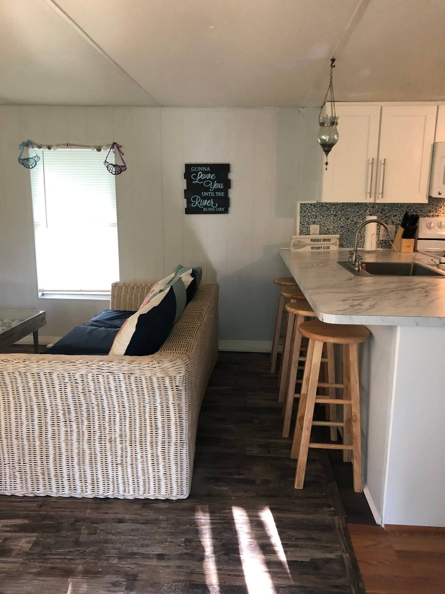 A living room with a couch and a kitchen with a sink.