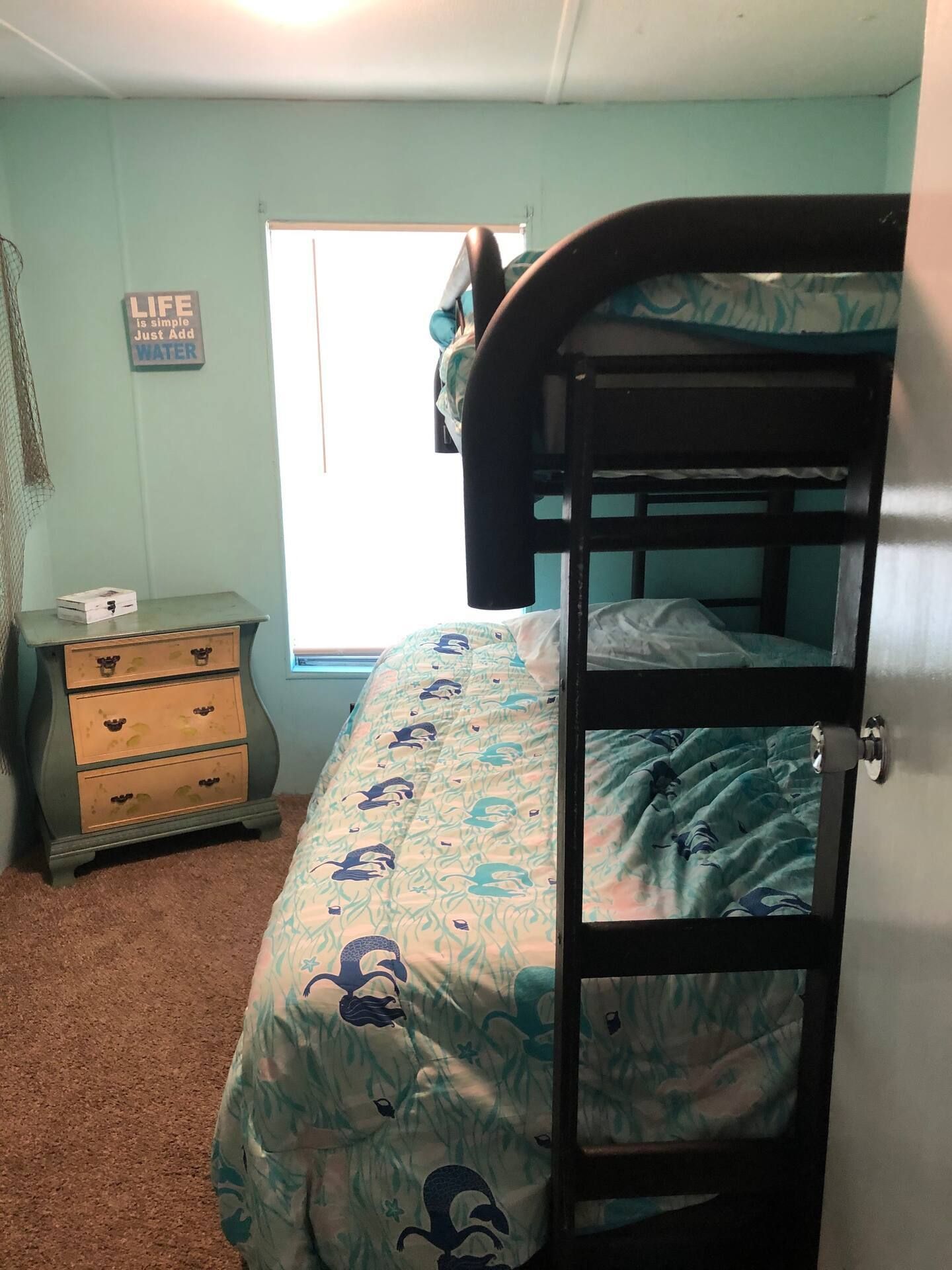 A bedroom with a bunk bed , dresser , and window.