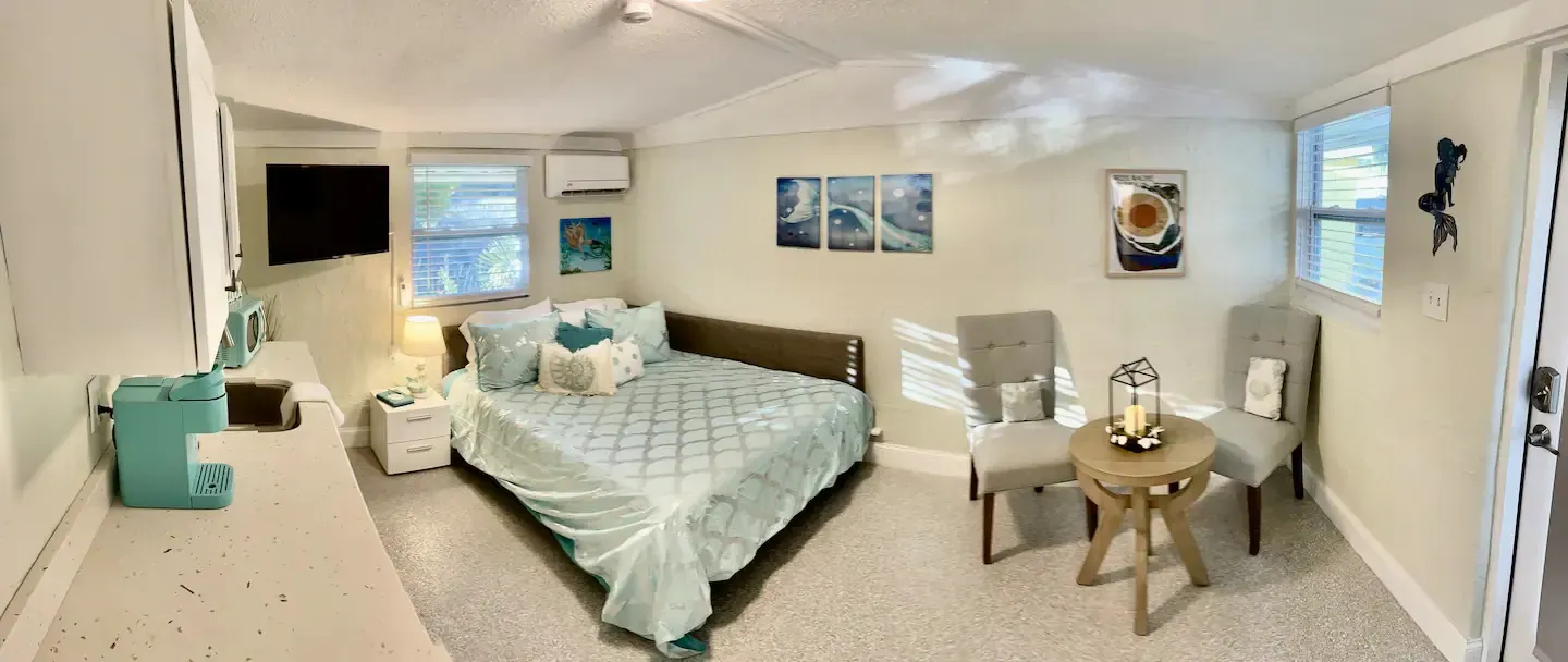 A bedroom with a bed , chairs , table and television.