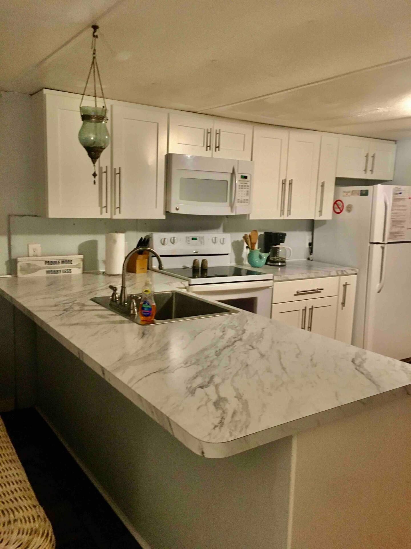 A kitchen with white cabinets and marble counter tops