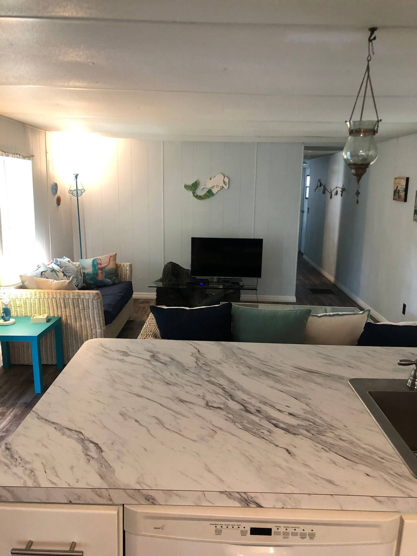 A kitchen with a marble counter top and a dishwasher.