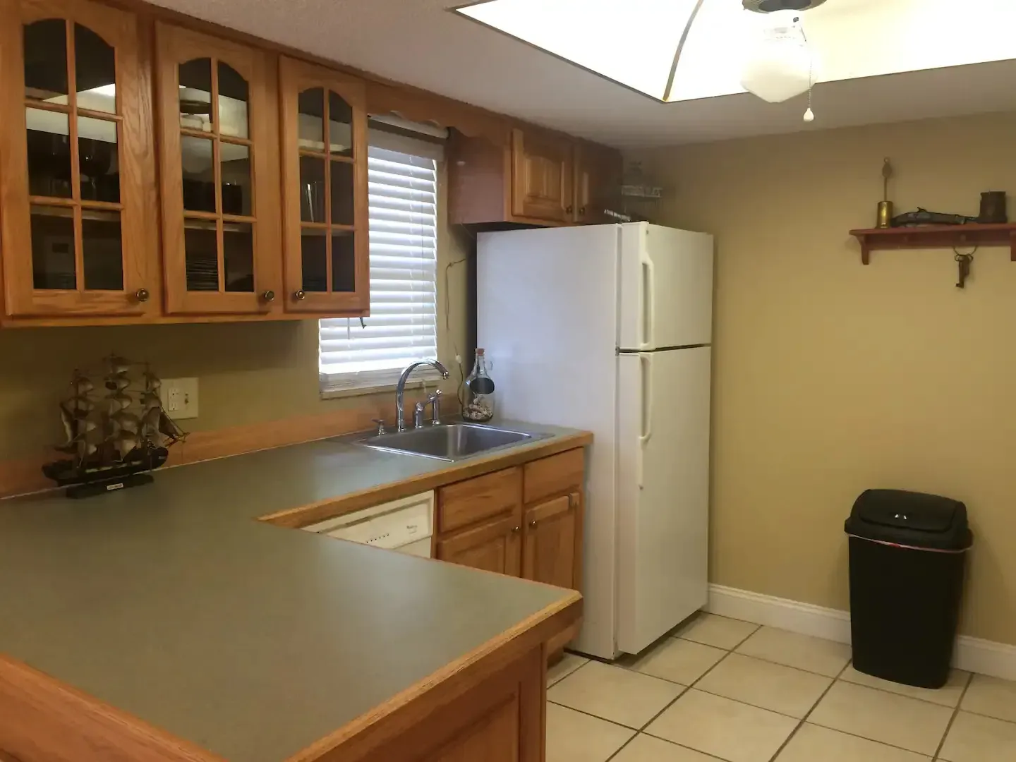 A kitchen with a sink , refrigerator , dishwasher and trash can.