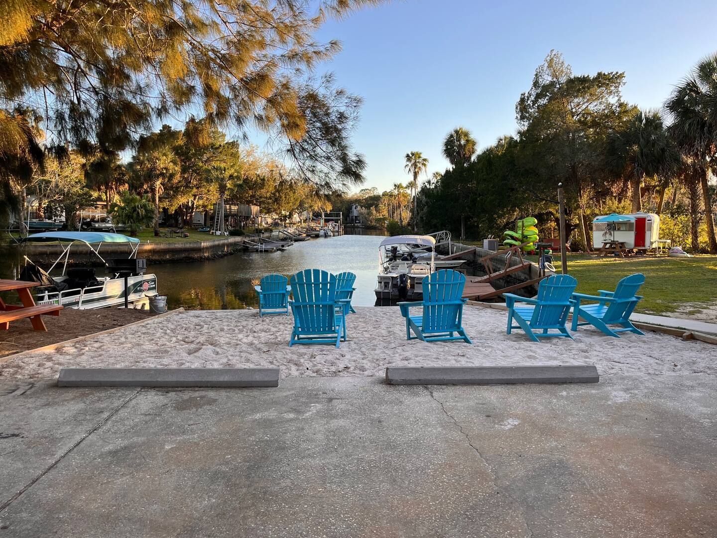 A group of blue chairs are sitting on a sandy beach next to a river.