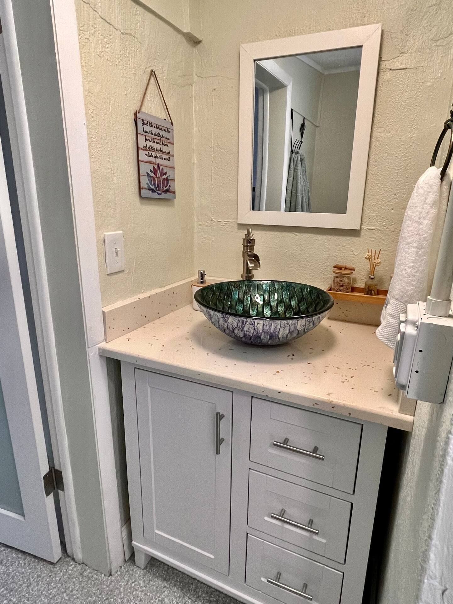 A bathroom with a sink , mirror and cabinets.