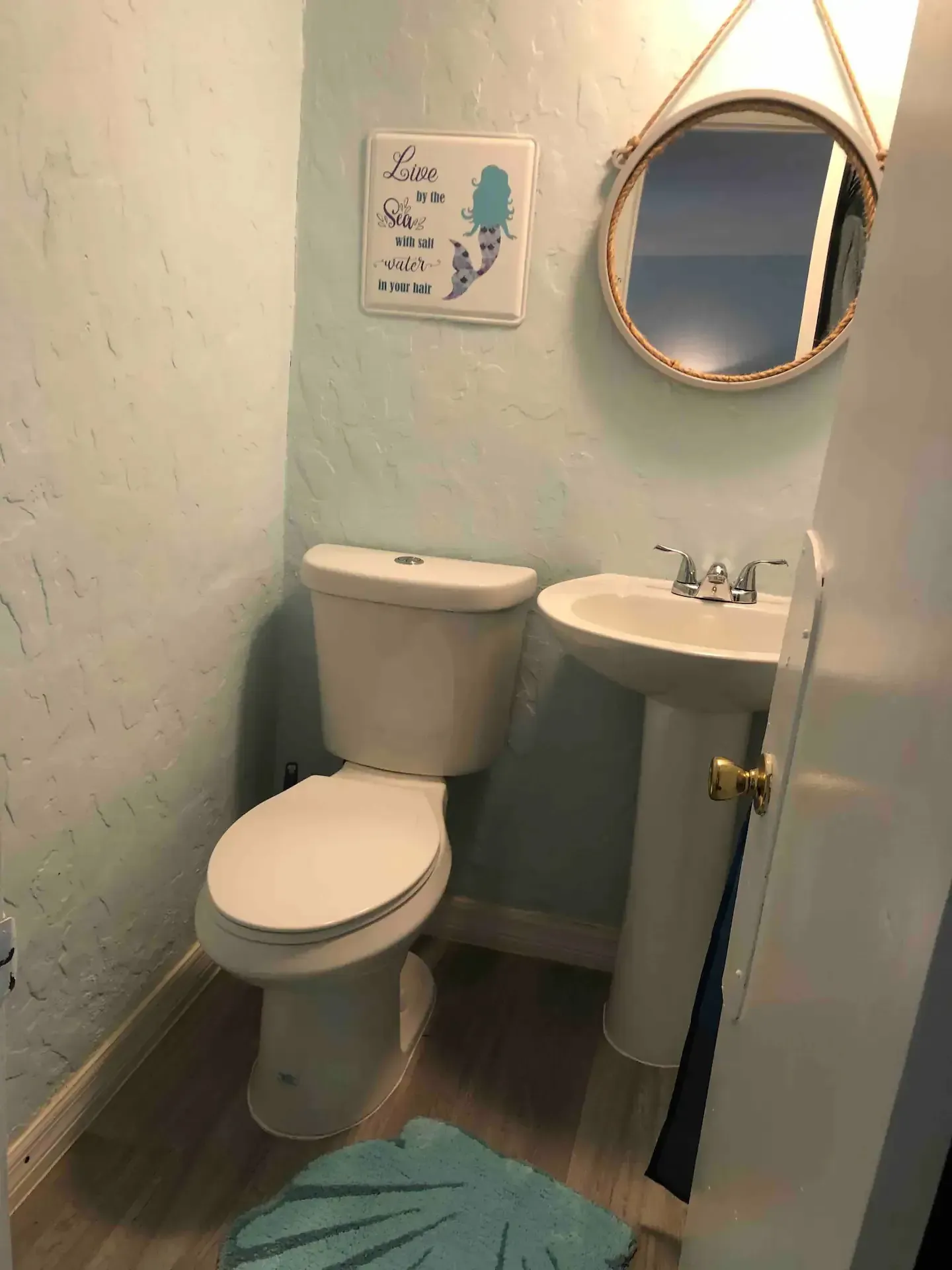 A bathroom with a toilet , sink and mirror.