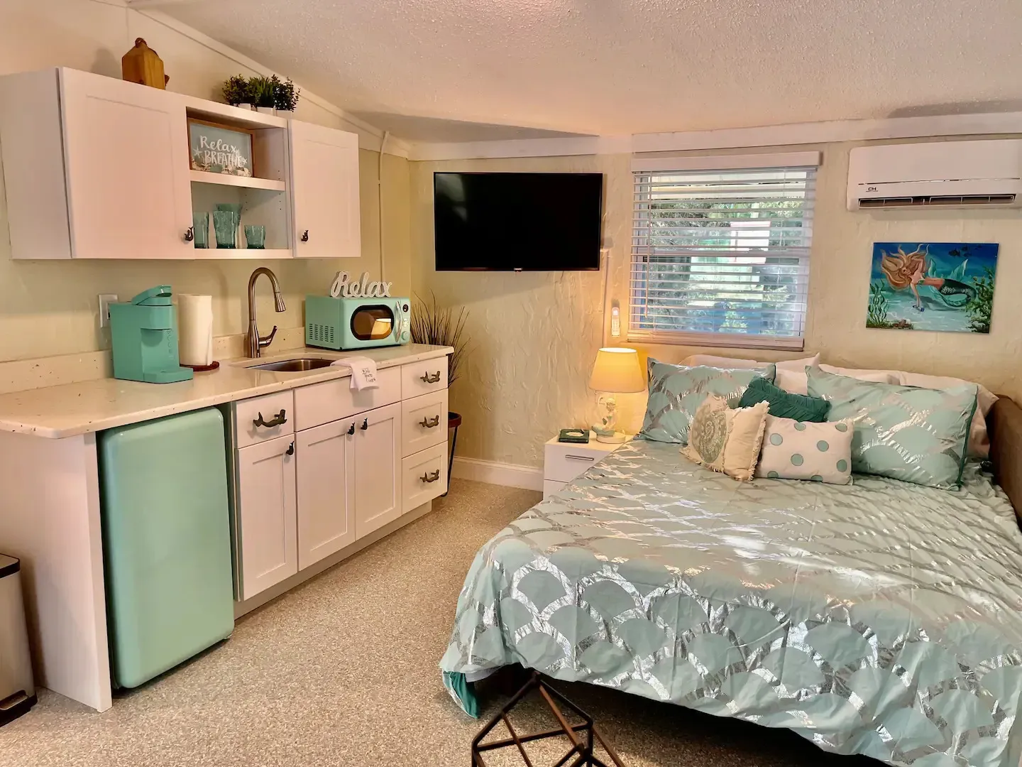 A bedroom with a bed , kitchen , and television.