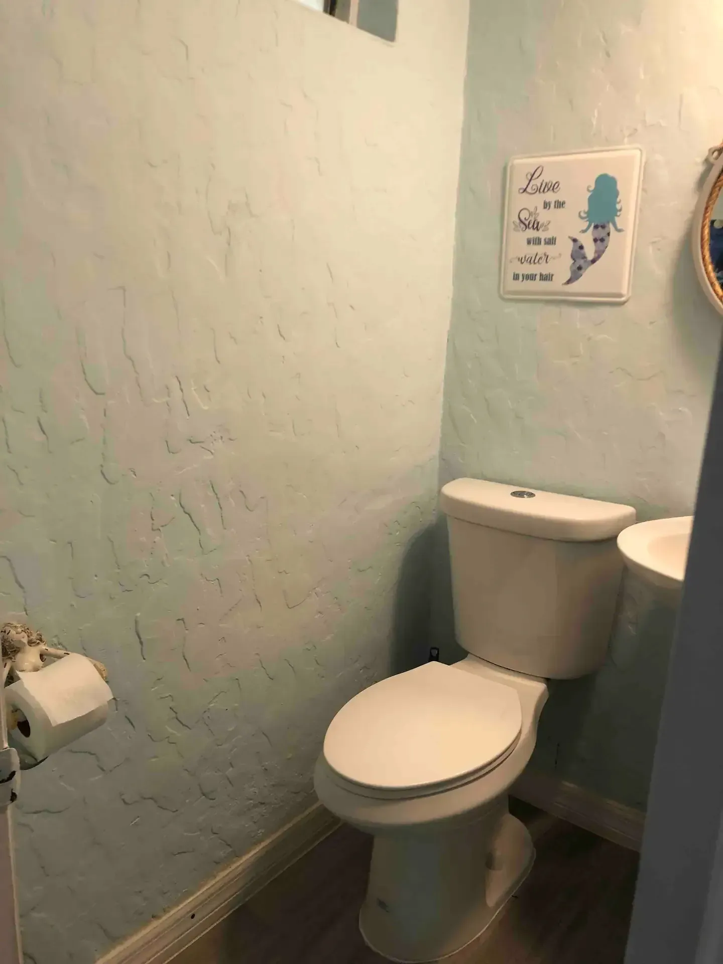 A bathroom with a toilet , sink and mirror.