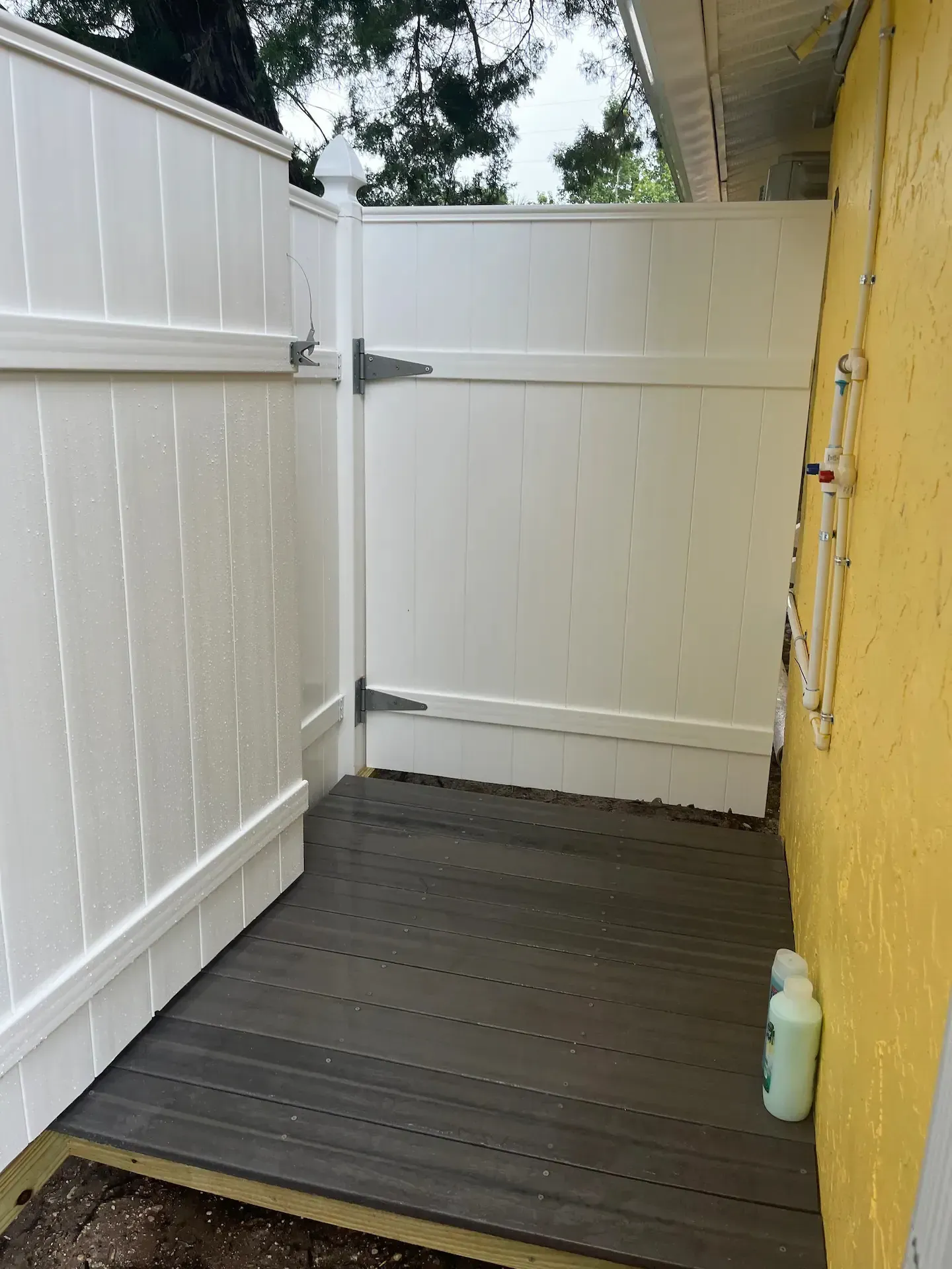 A white fence is surrounding a wooden deck.
