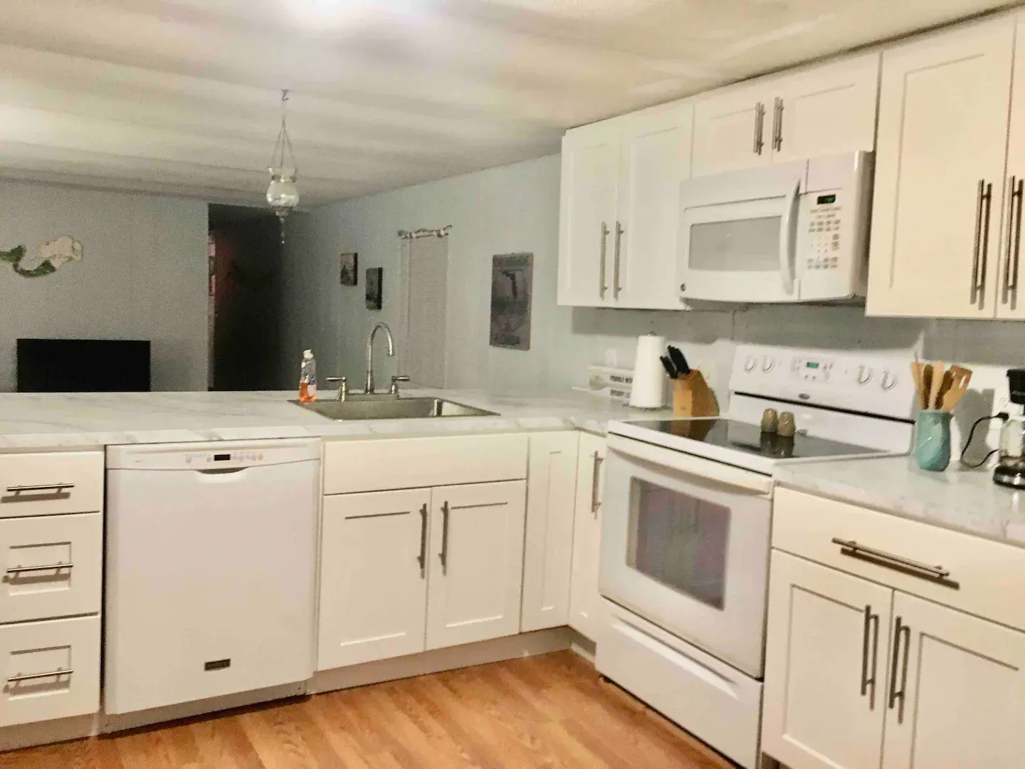 A kitchen with white cabinets , a stove , a microwave , and a sink.