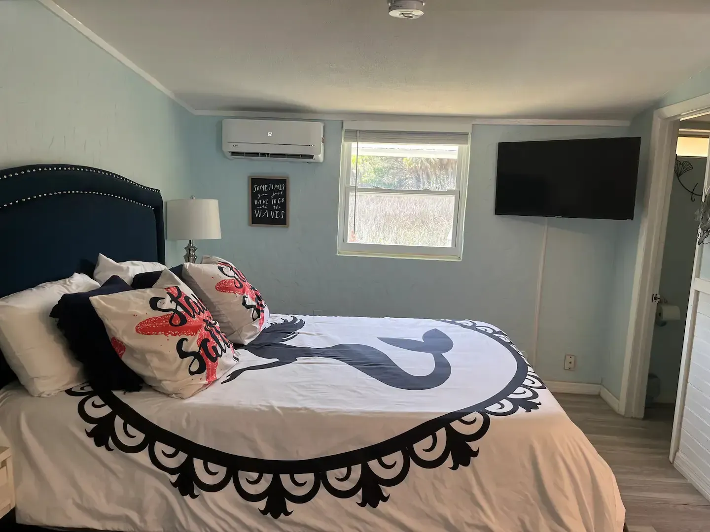 A bedroom with a bed , television and air conditioner.
