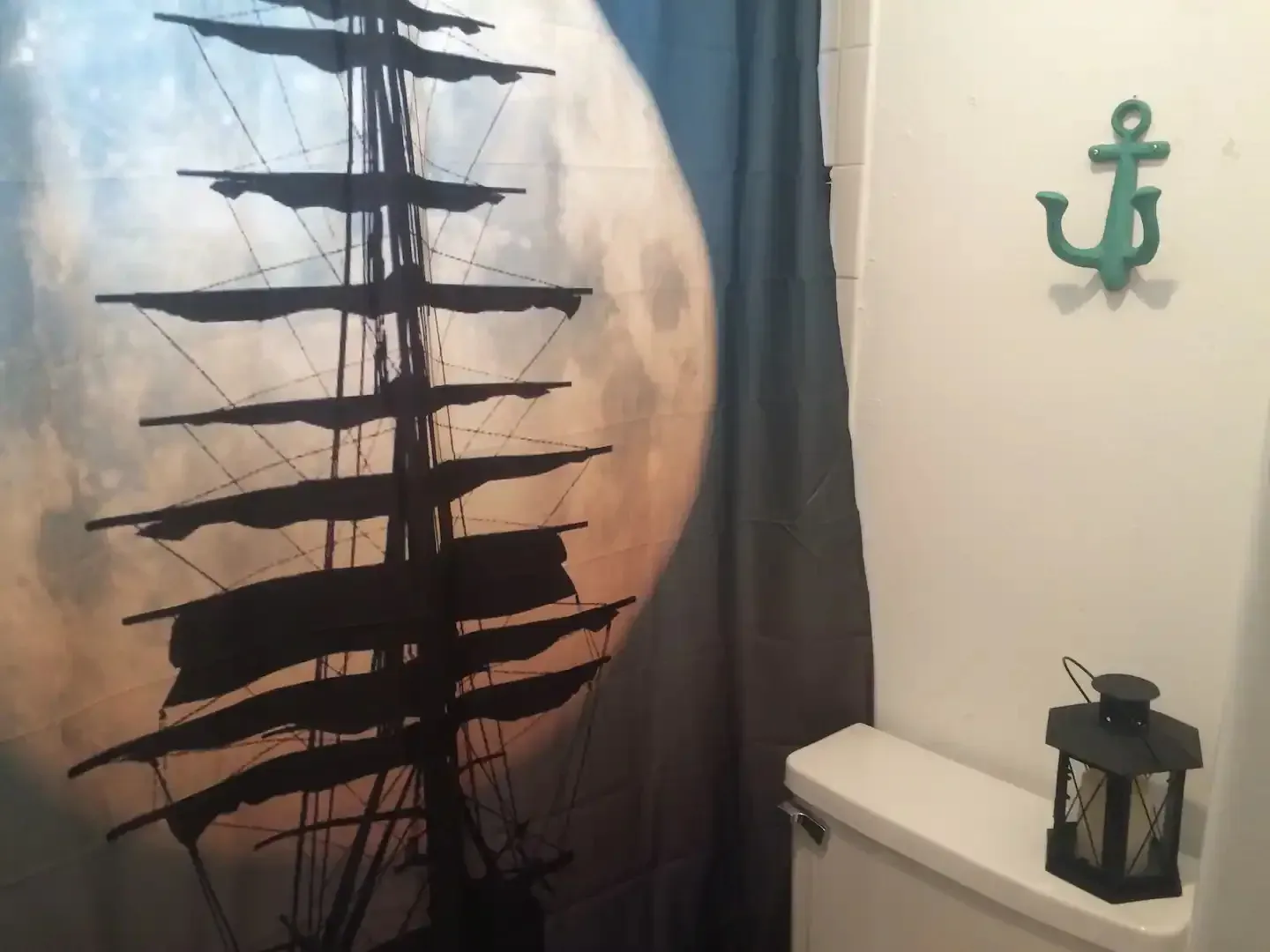 A bathroom with a shower curtain with a sailboat on it