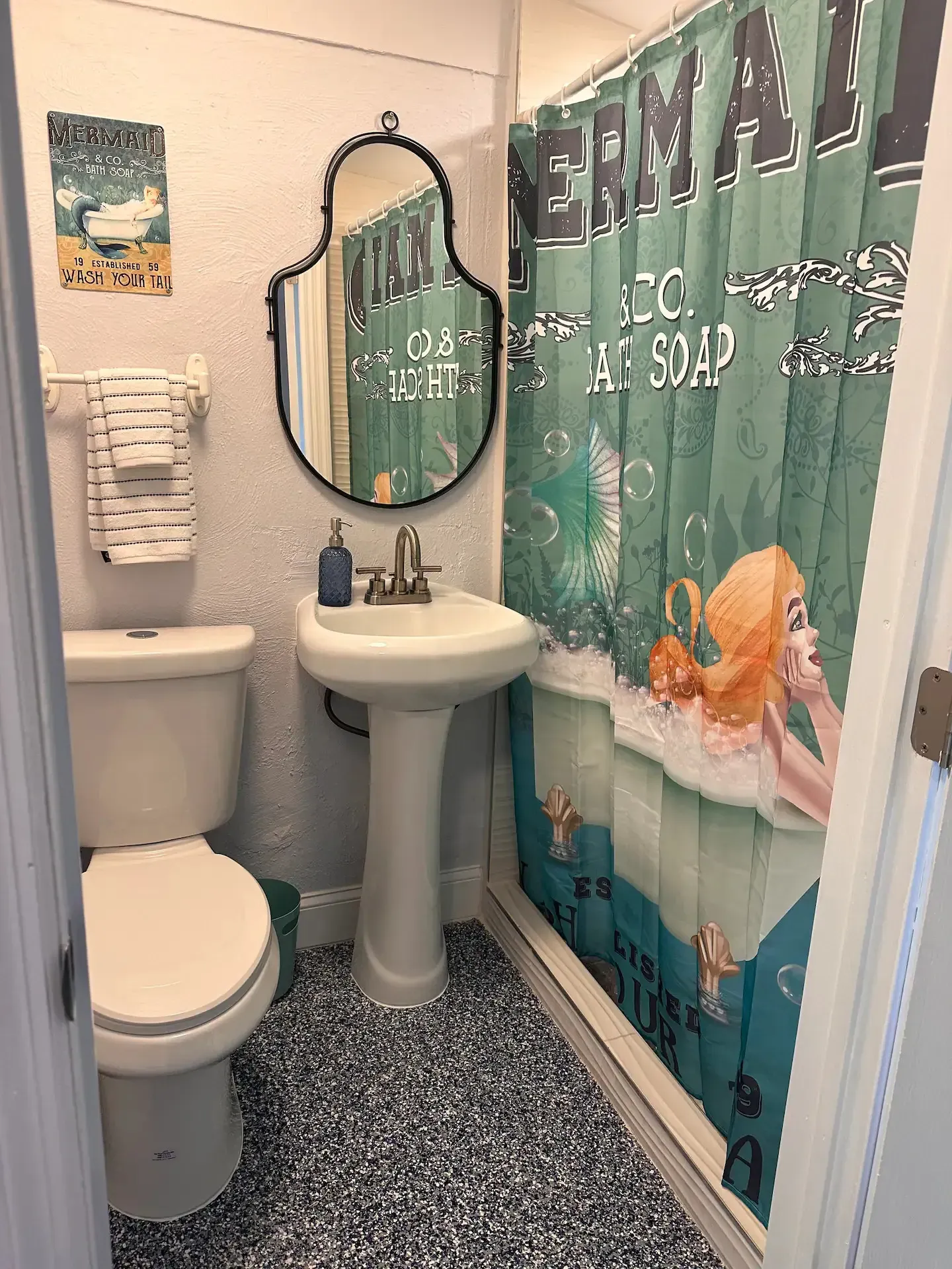 A bathroom with a toilet , sink , mirror and shower curtain.