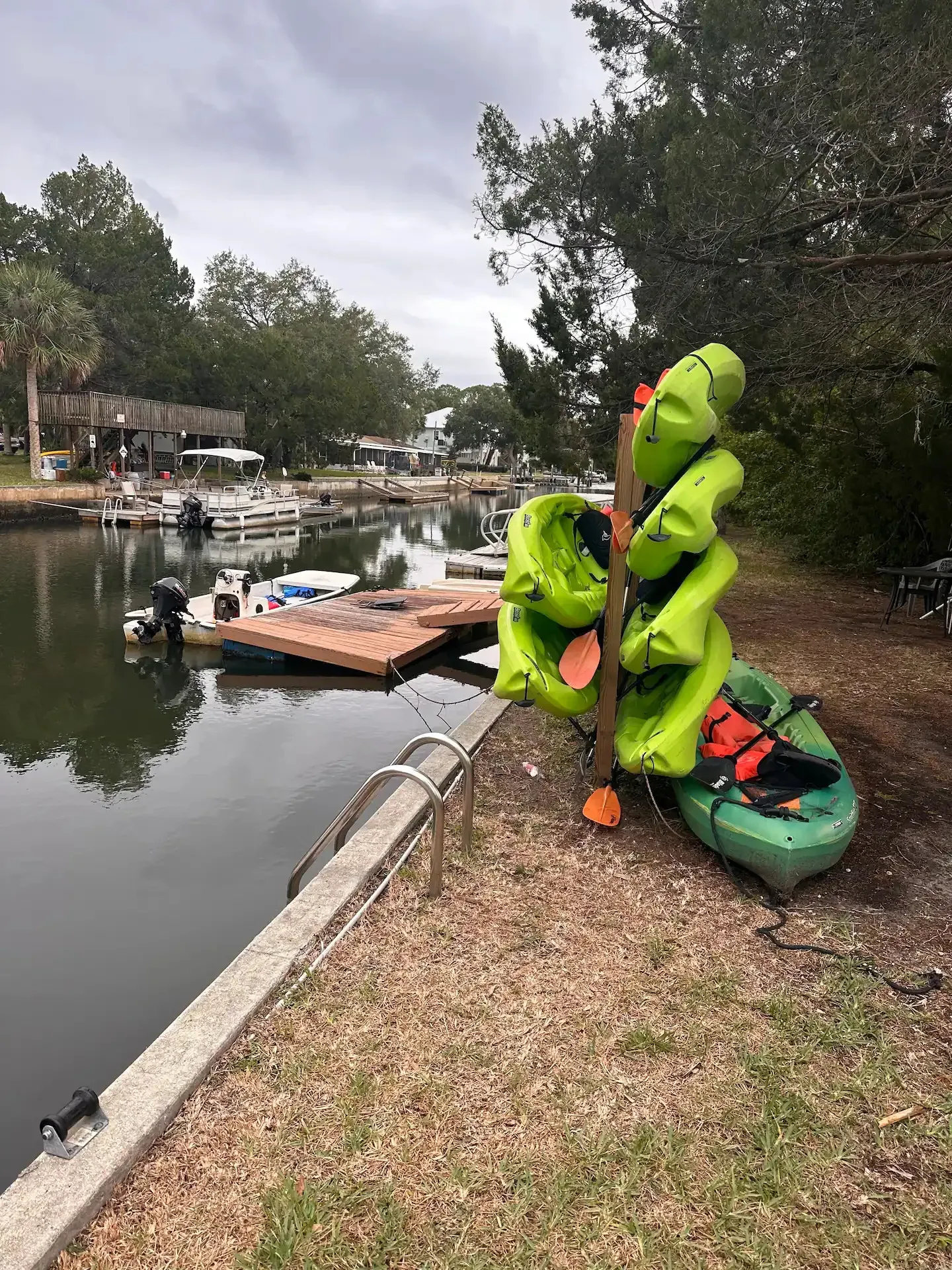 A bunch of kayaks are sitting on the ground next to a body of water.