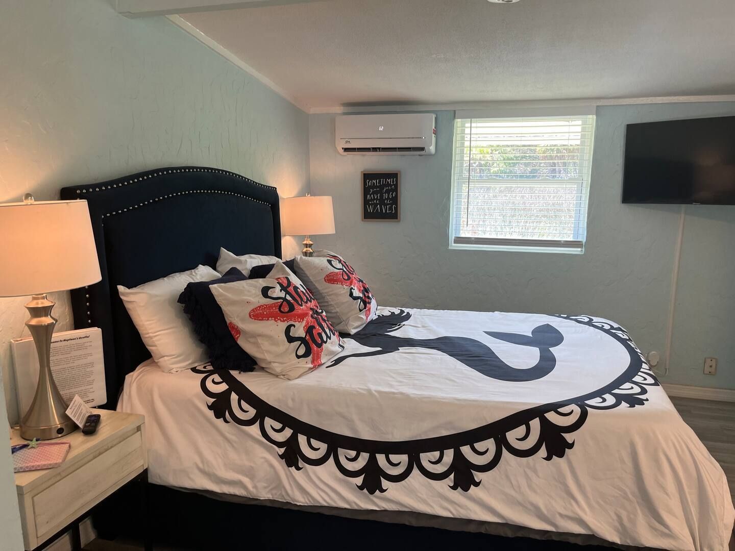 A bedroom with a bed , lamps , a television and a window.