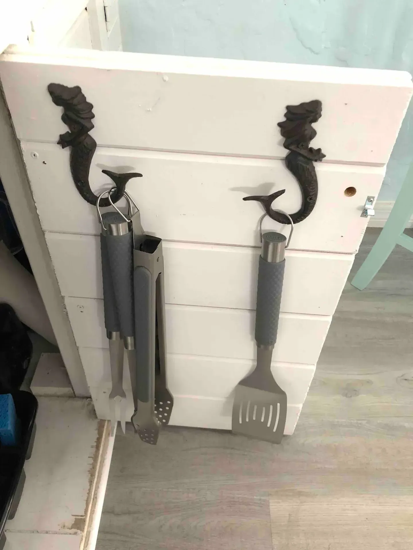 A pair of grilling utensils hanging on a white door.