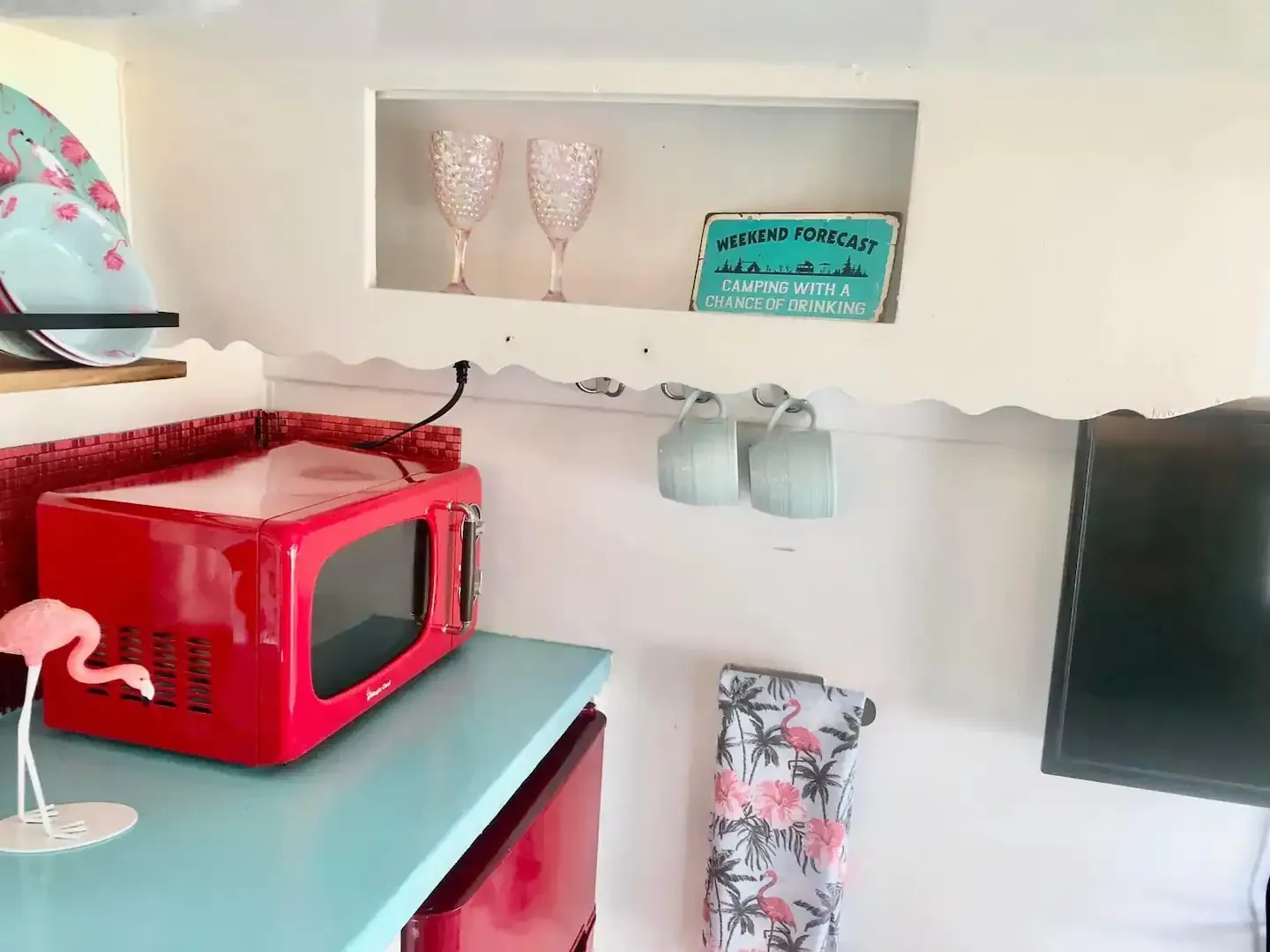 A red microwave is sitting on a blue counter in a kitchen.