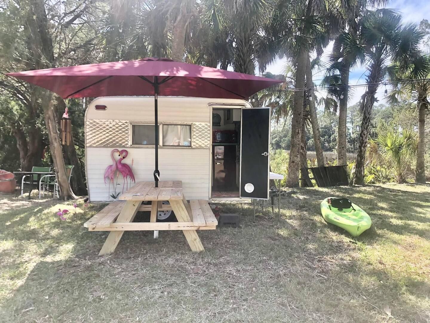 A trailer with a picnic table and umbrella in front of it.