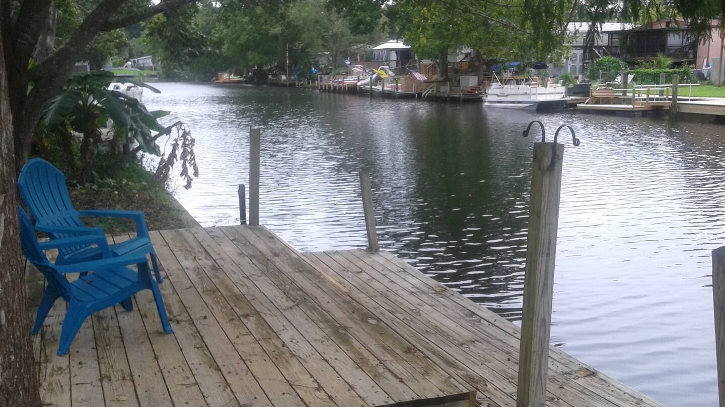 A blue chair is sitting on a wooden deck next to a body of water.