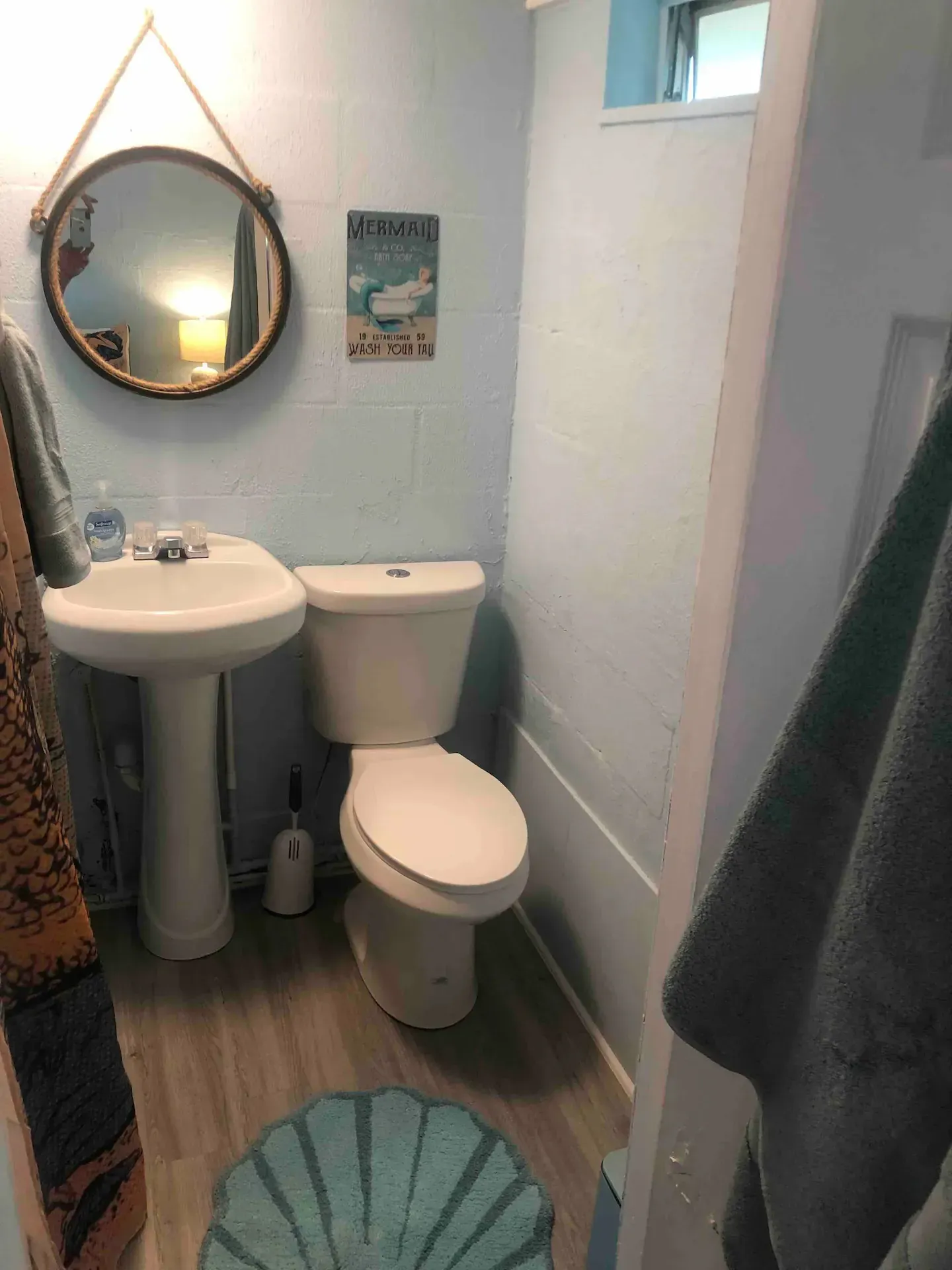 A bathroom with a toilet , sink and mirror.