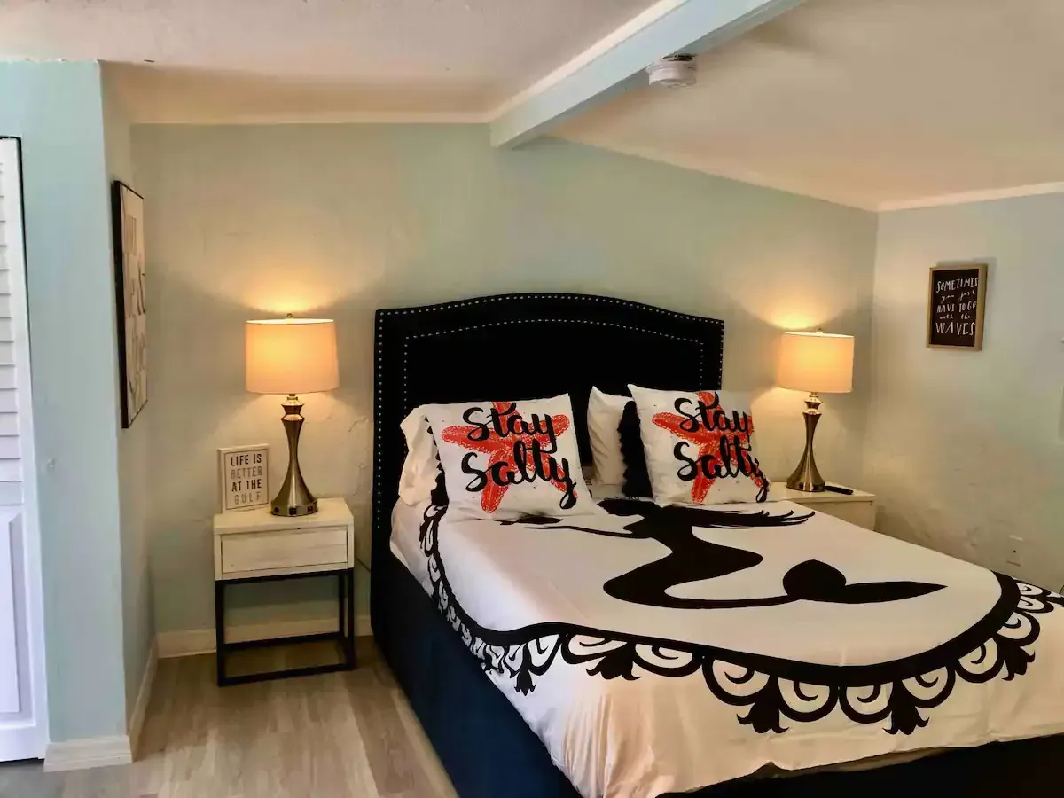 A bedroom with a bed and pillows that say stay salty