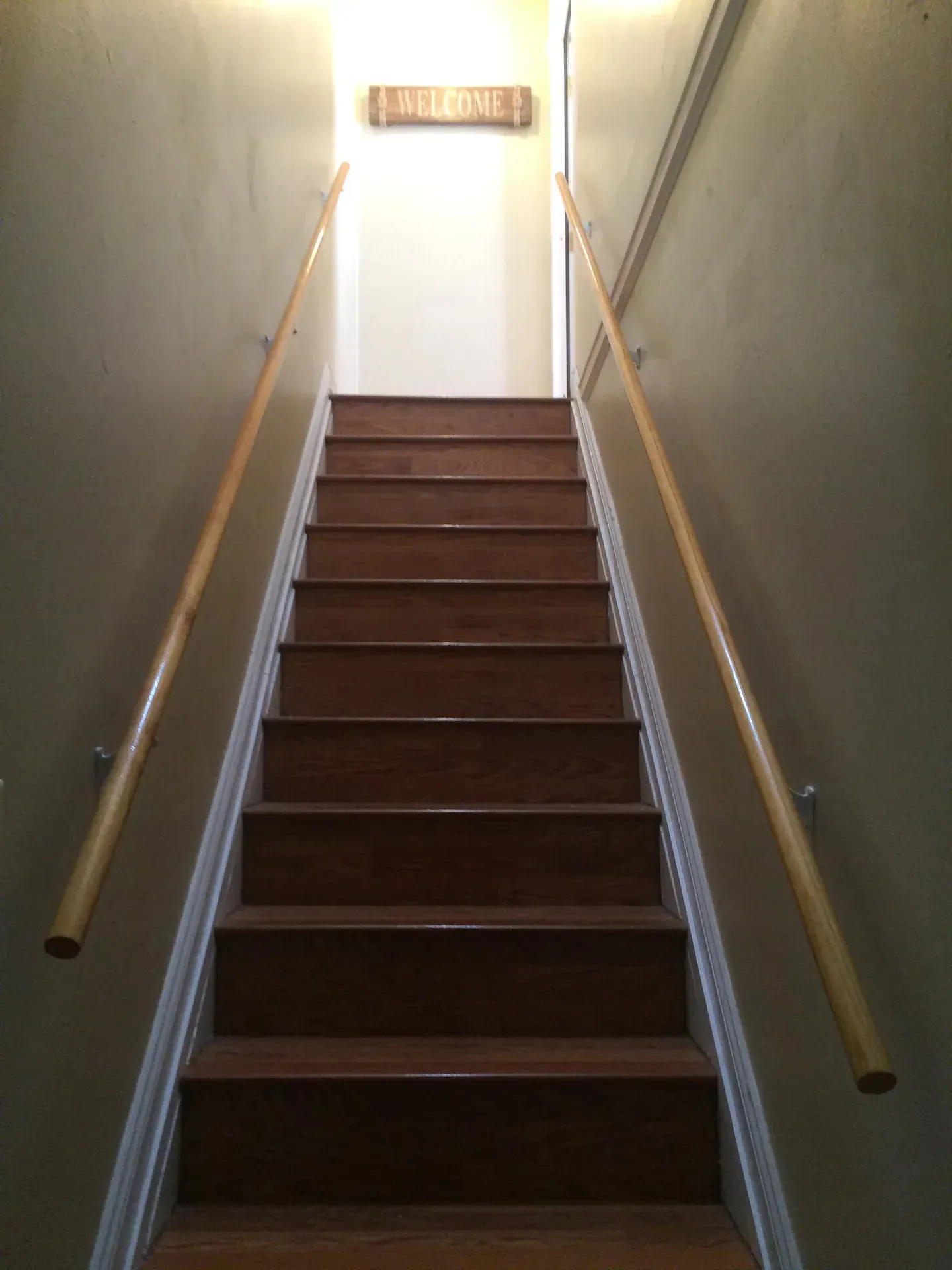 A wooden staircase with a sign on the wall that says welcome