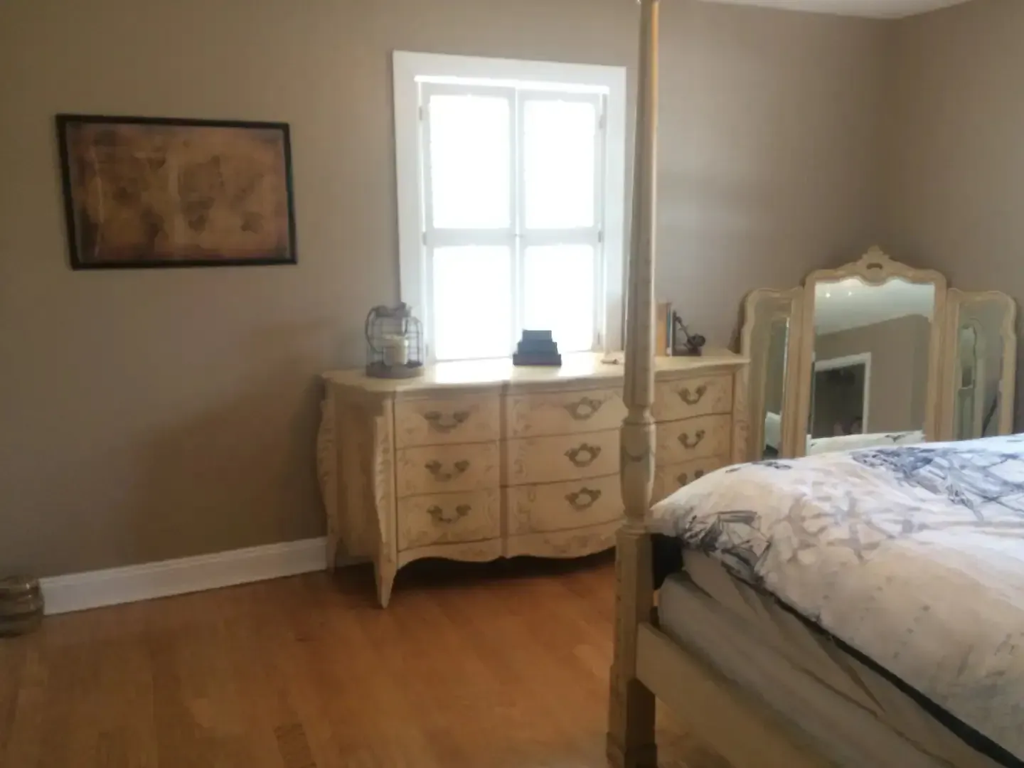 A bedroom with a four poster bed dresser and mirror