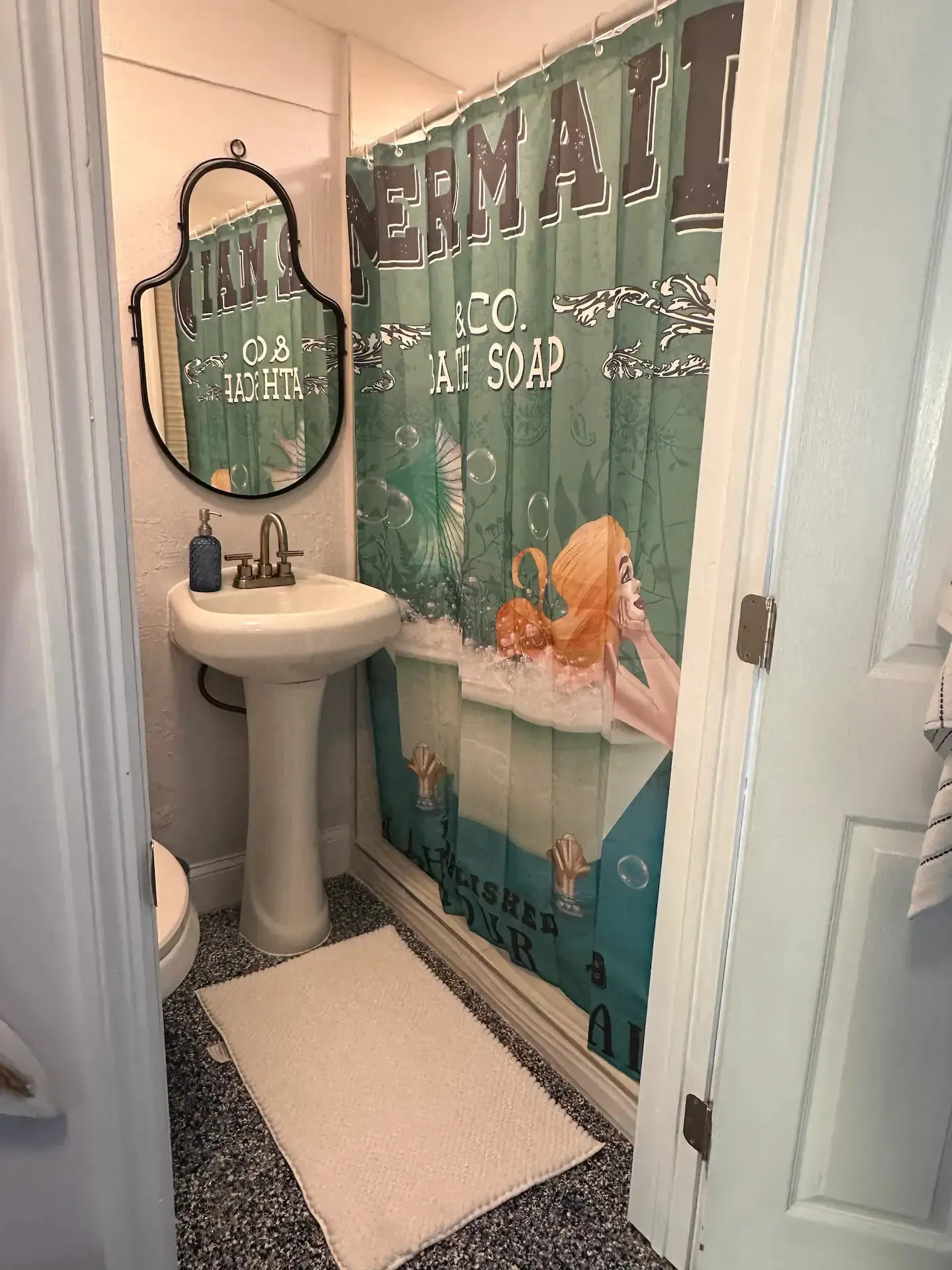 A bathroom with a sink , toilet , mirror and shower curtain.
