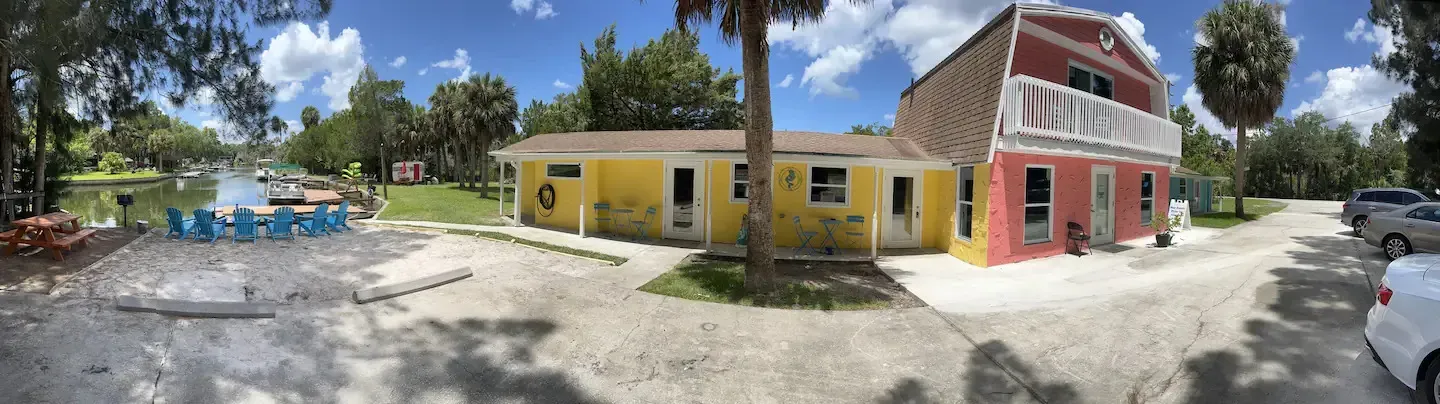 A panoramic view of a yellow and red house surrounded by trees.
