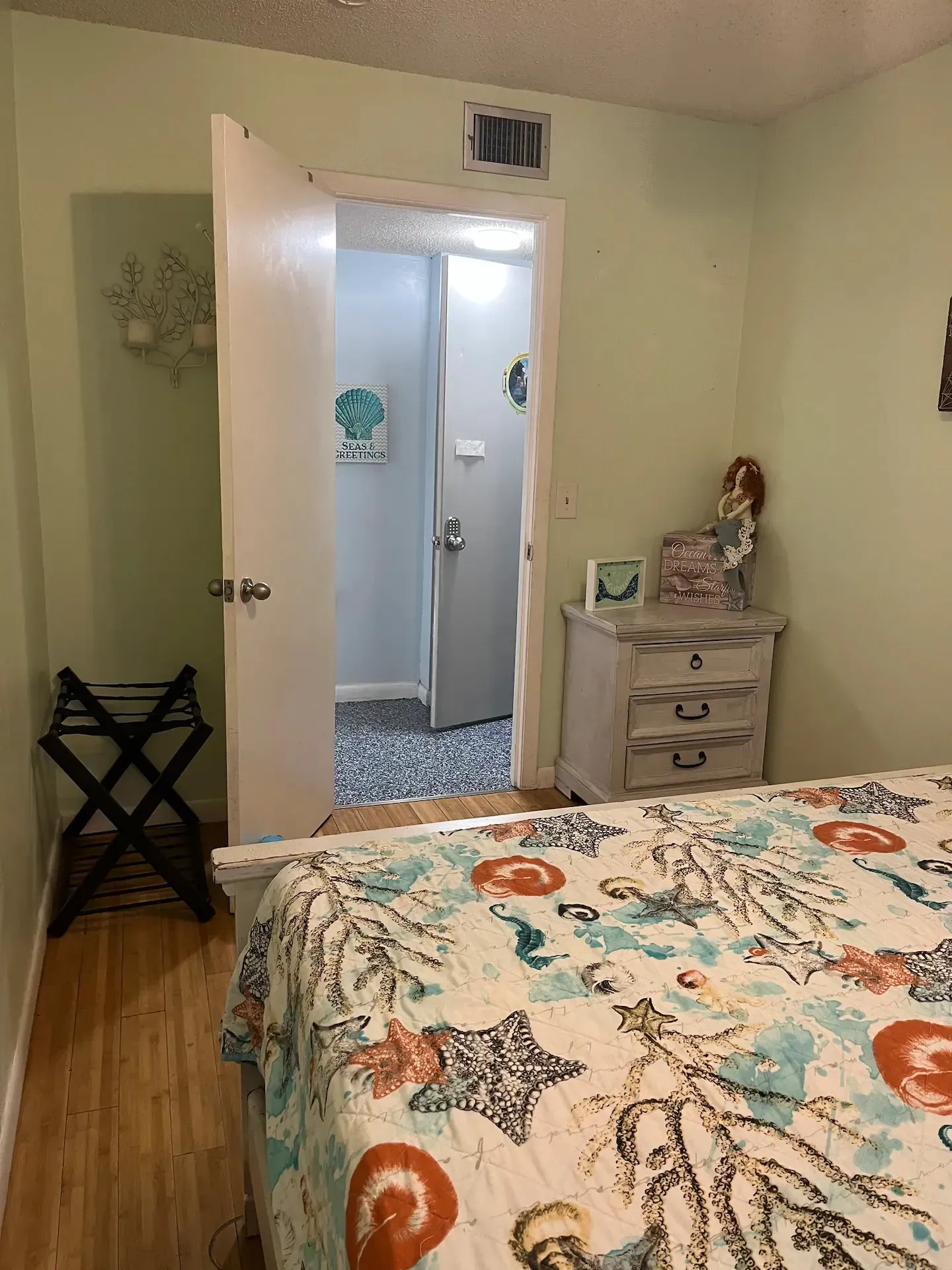 A bedroom with a bed , dresser , nightstand and door leading to a bathroom.