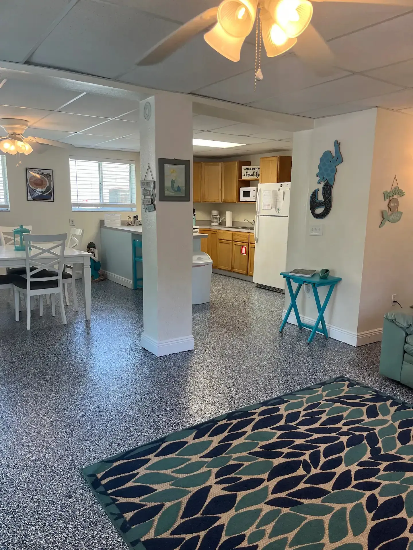 A living room with a rug on the floor and a ceiling fan.