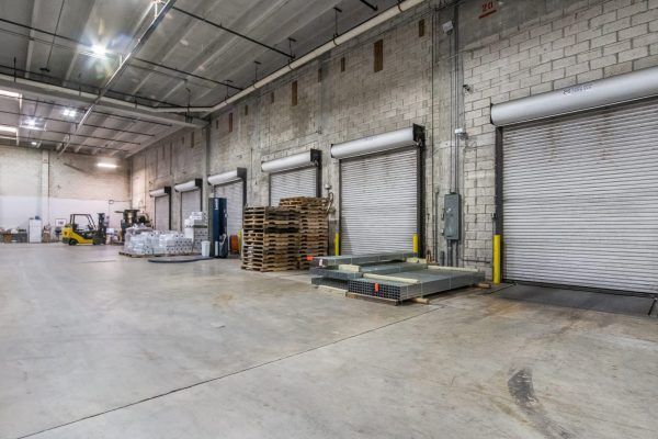 A large warehouse with a lot of doors and a forklift.