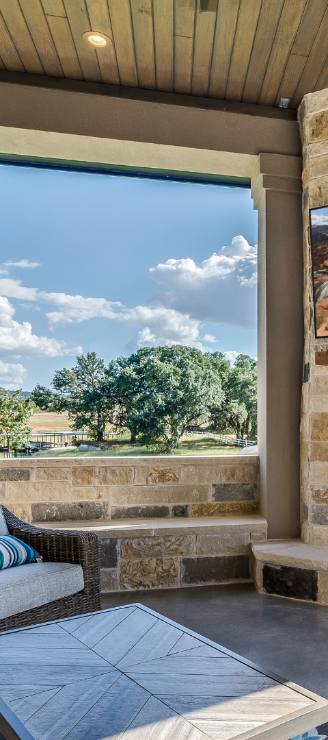 Outdoor patio with a view of blue sky, trees, and a stone wall.