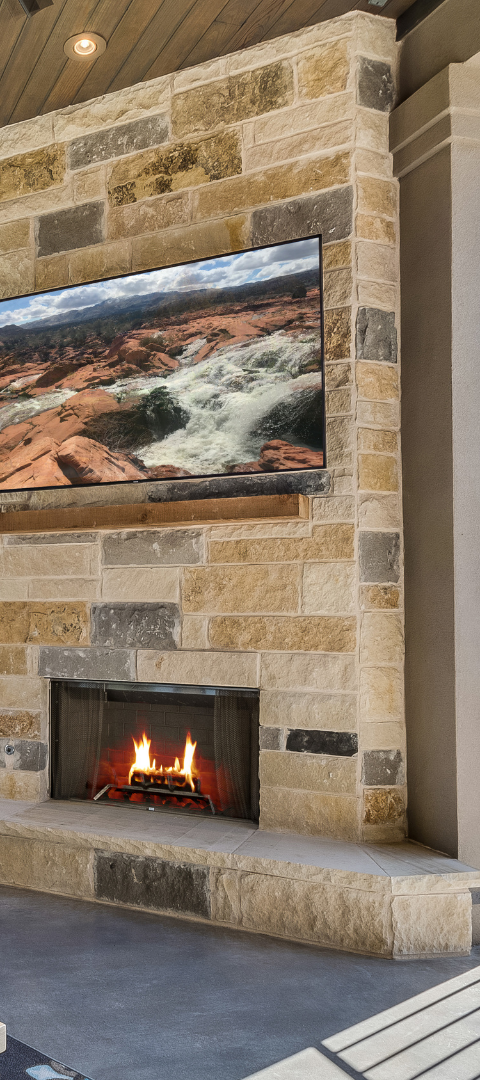 Stone fireplace with a lit fire and a mounted TV.