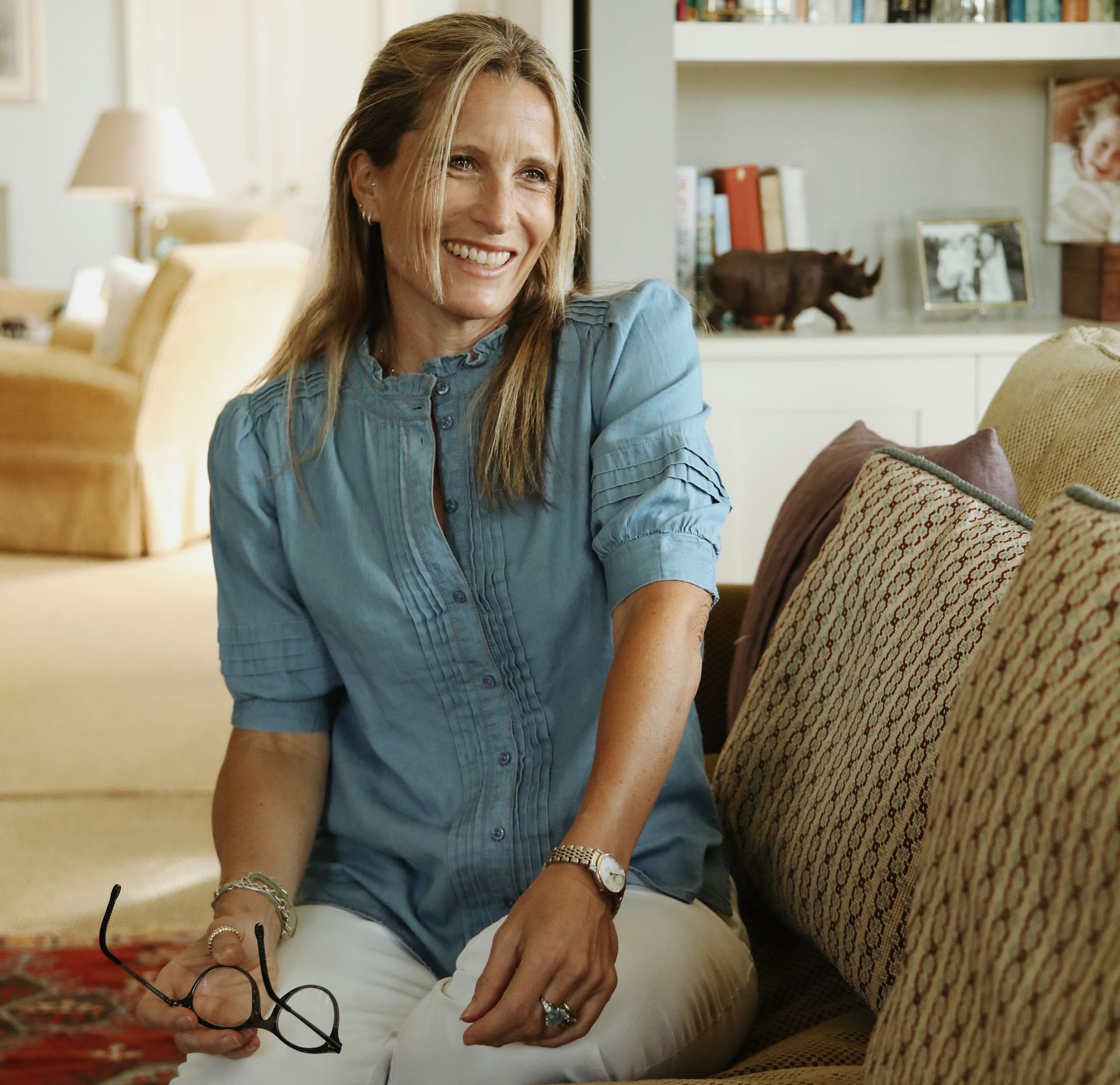 A woman in a blue shirt is sitting on a couch