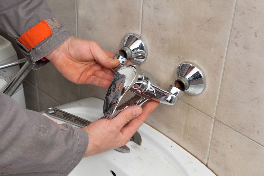 A man is fixing a faucet in a bathroom — Hydro Excavation in Canberra, NSW