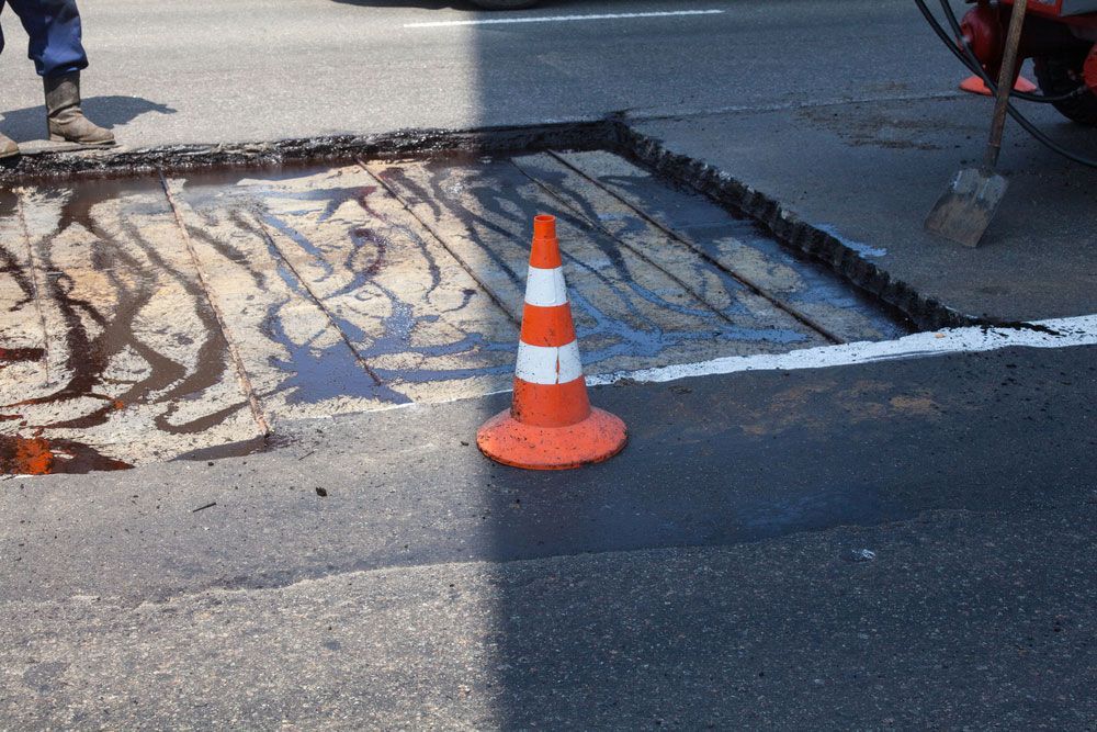 An orange and white traffic cone is sitting on the side of the road — Hydro Excavation in Canberra, NSW
