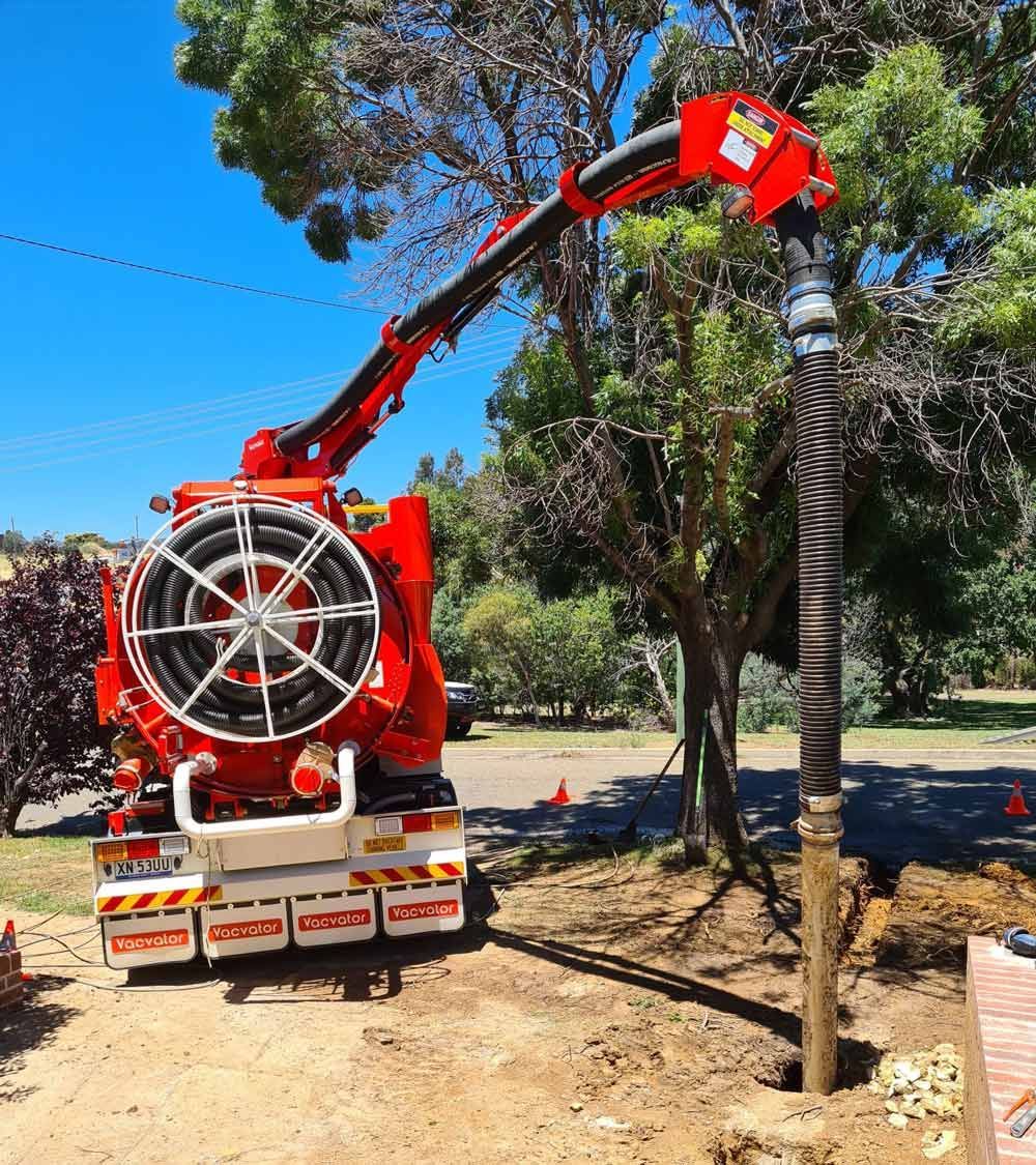 A Red Vacuum Truck With A Hose Attached To It Is Parked In A Yard — Hydro Excavation in Goulburn, NSW