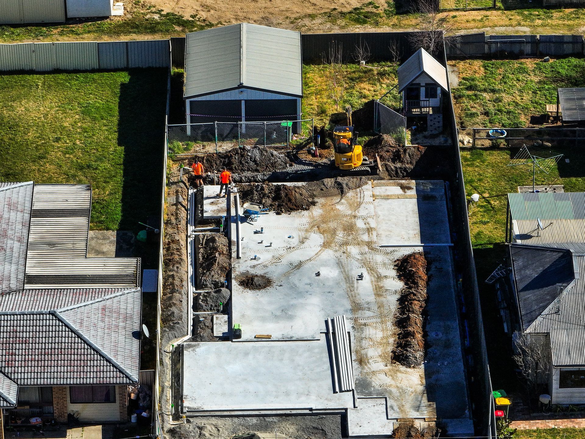 A construction site with a yellow excavator and workers 
— Hydro Excavation in Goulburn, NSW